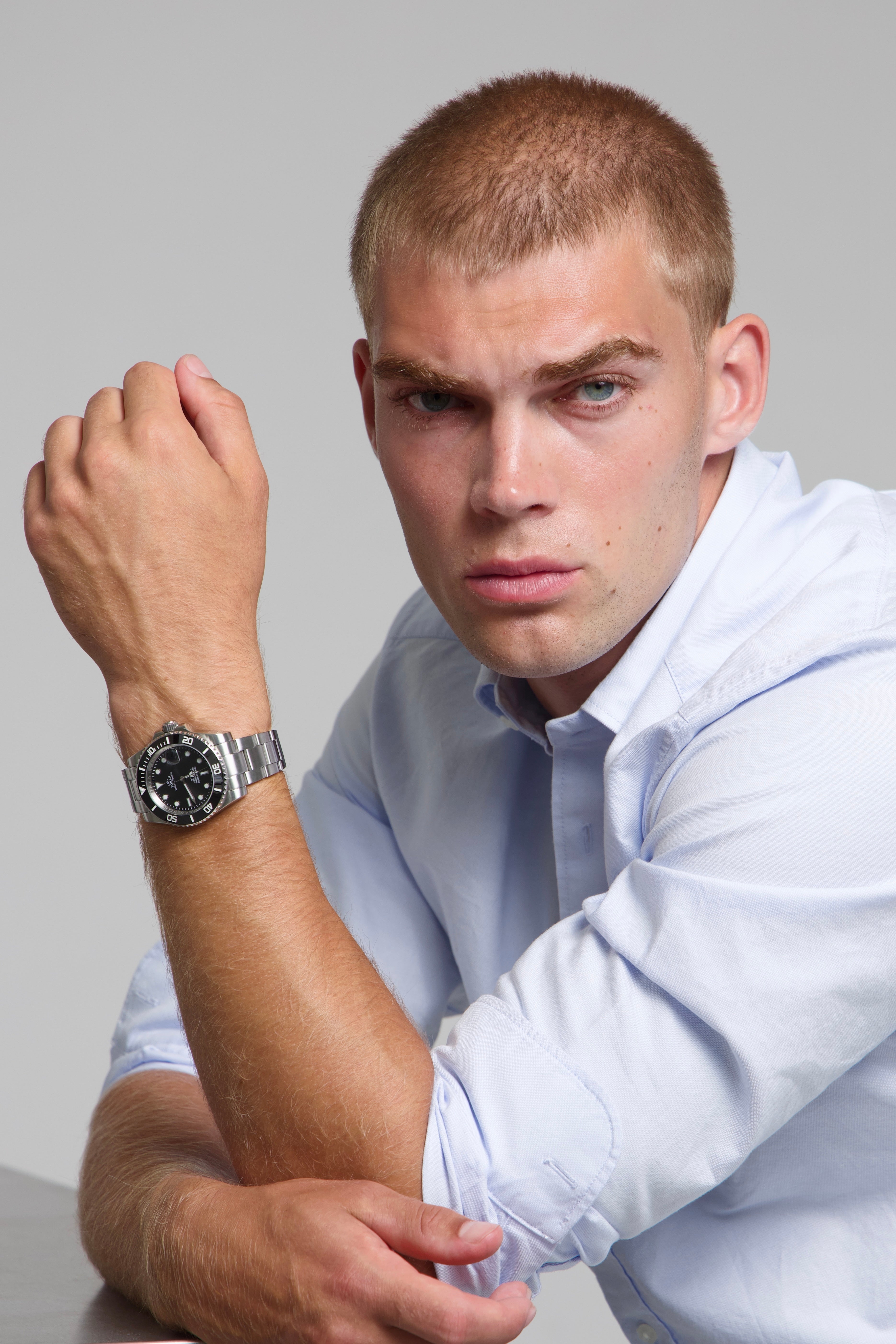 Man wearing a SOREN oceanic black watch on a oyster bracelet, seated with his arm on a table