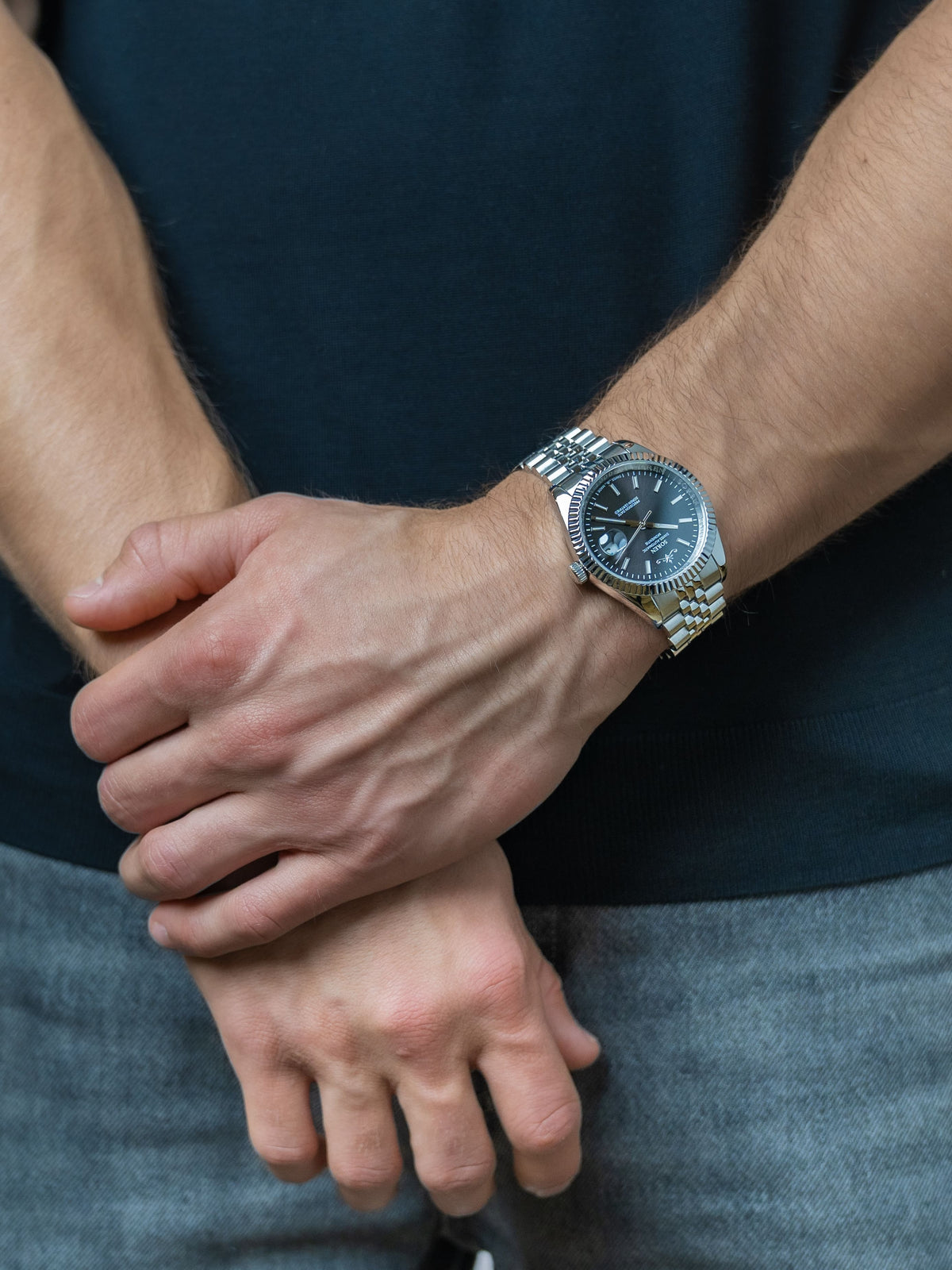 SOREN Momentis Swiss automatic watch with black dial on a 5-link steel bracelet, shown with hands clasped together