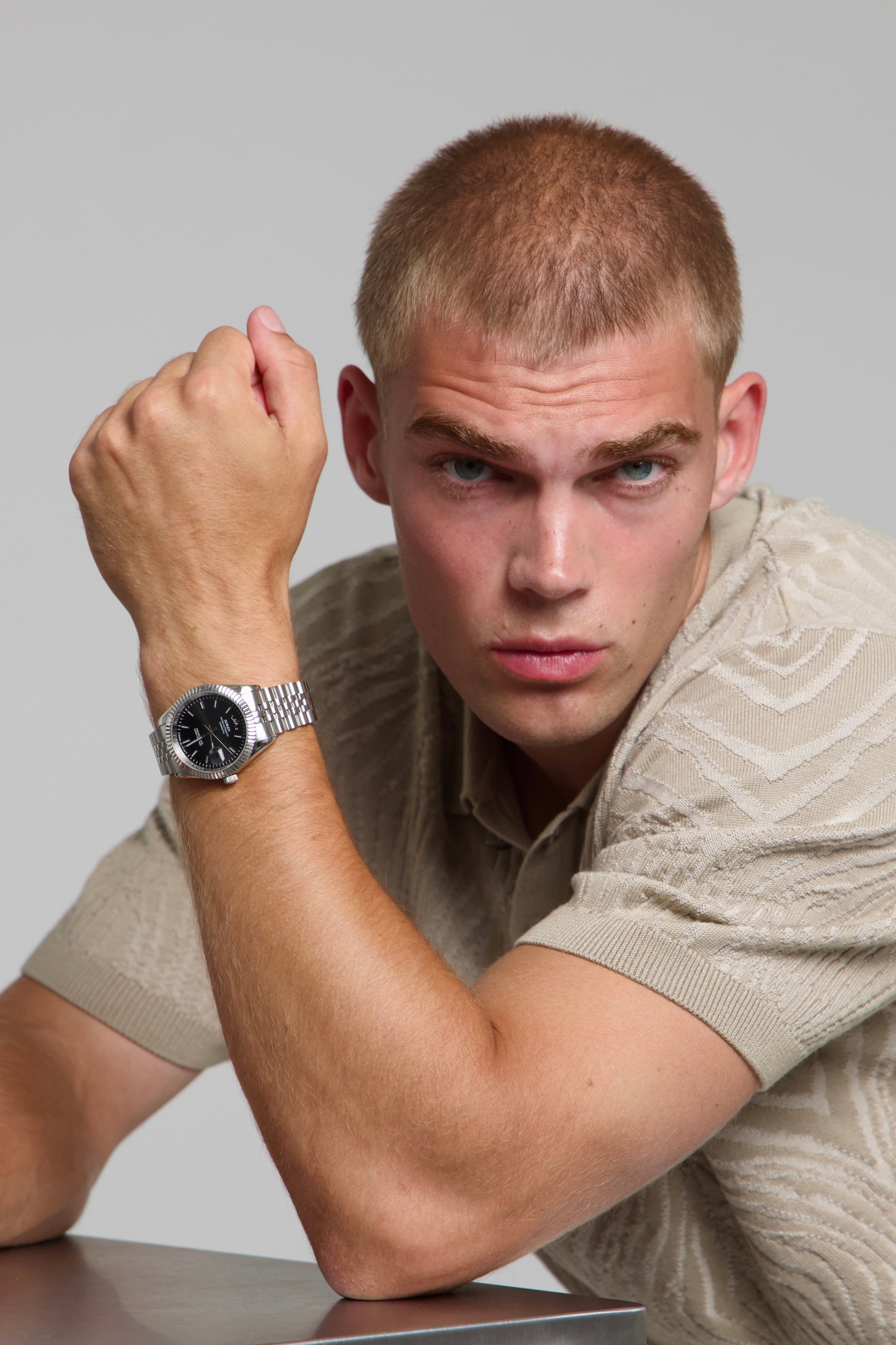 Man wearing a SOREN Momentis black watch on a jubilee bracelet, seated with his arm on a table.
