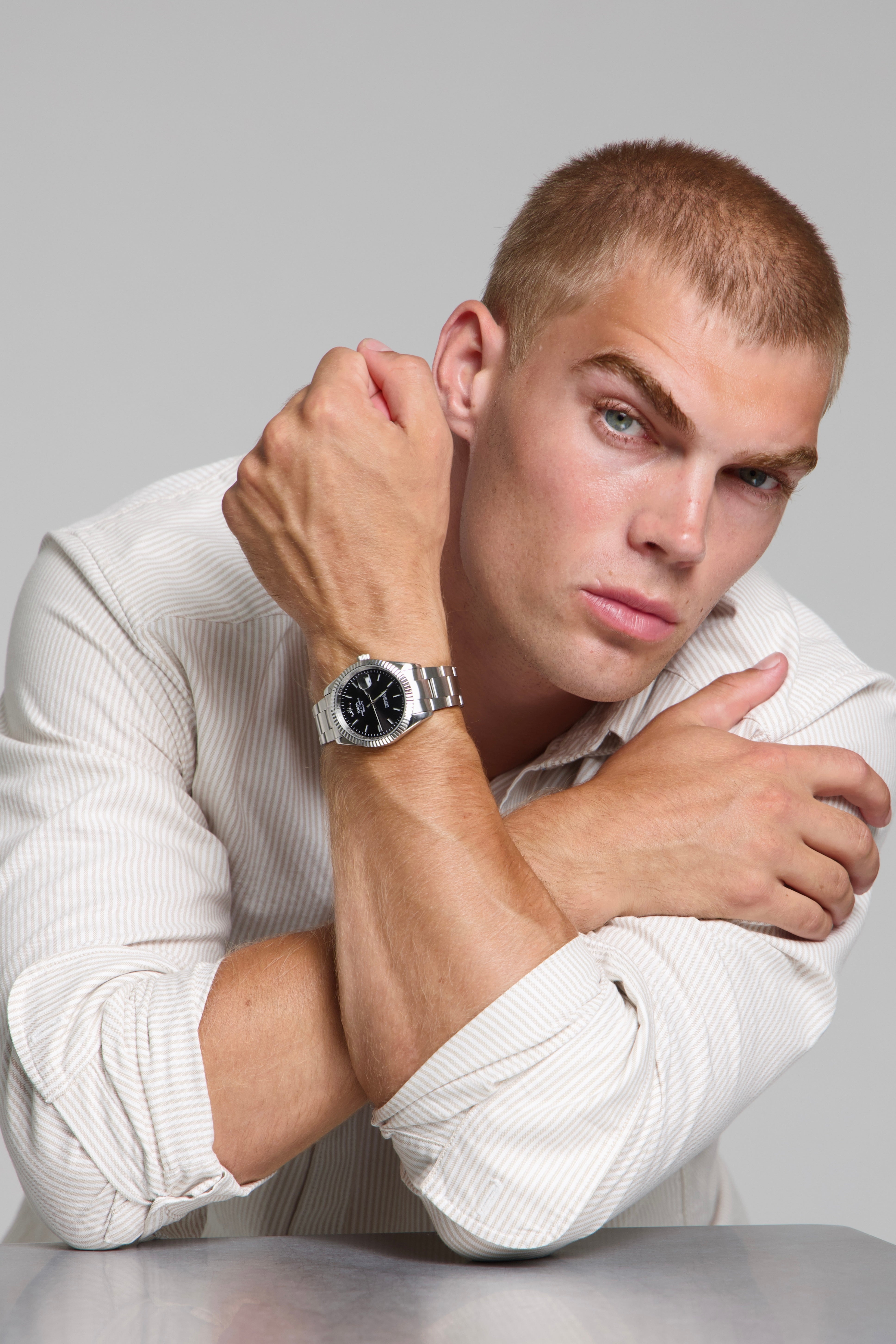 Man wearing a SOREN Momentis black watch on a oyster bracelet, seated with his arms on a table