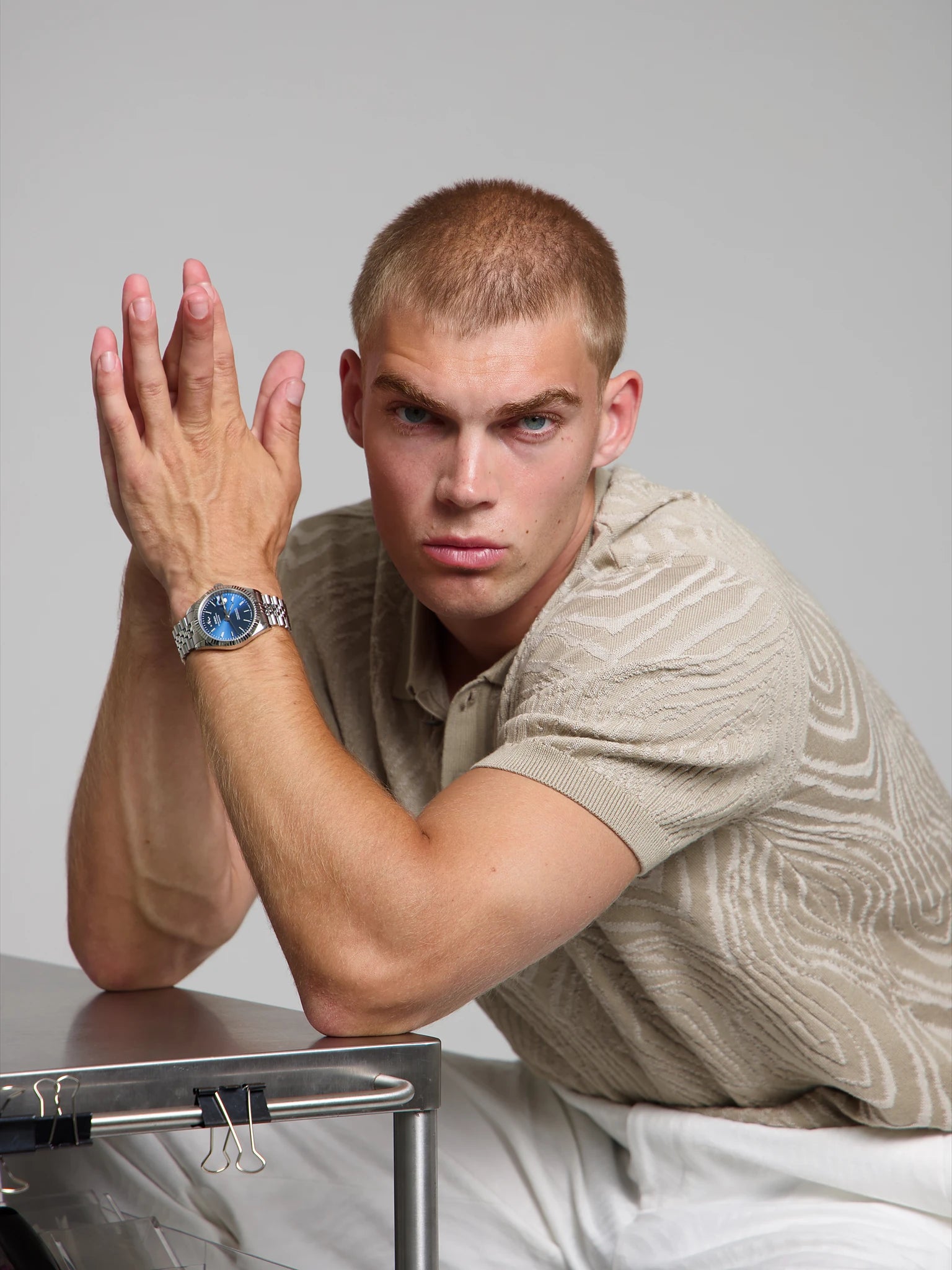 Man wearing a SOREN Momentis blue watch on a jubilee bracelet, seated with his arm on a table