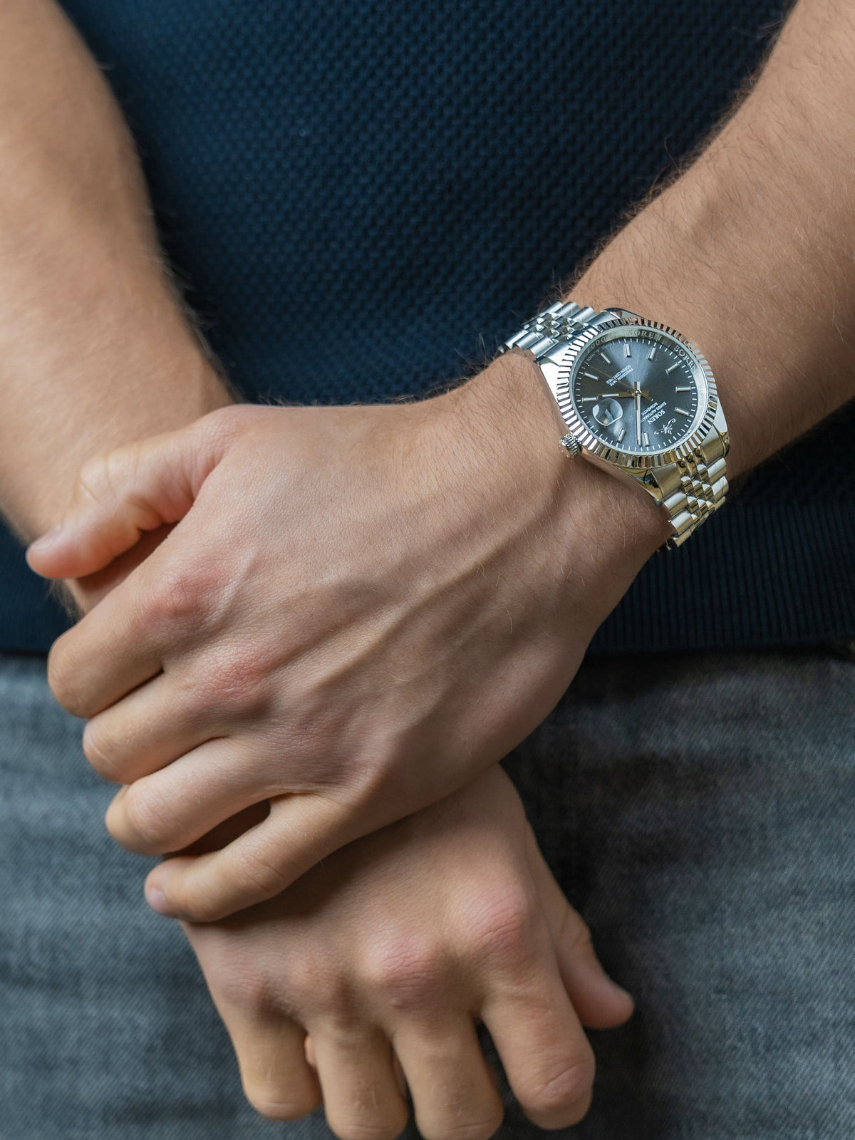 SOREN Momentis Swiss automatic watch with grey dial on a 5-link steel bracelet, shown with hands clasped together