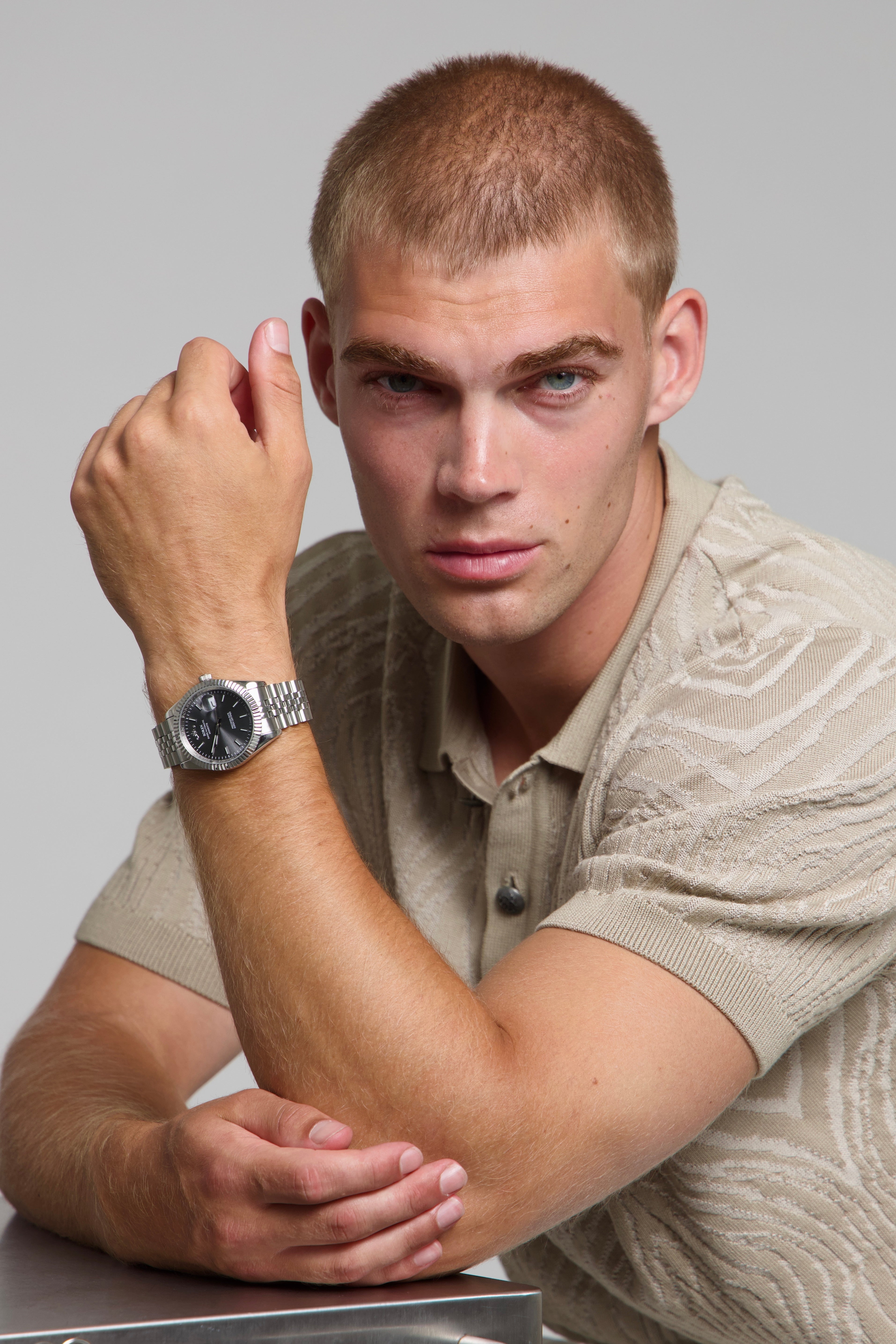 Man wearing a SOREN Momentis grey watch on a jubilee bracelet, seated with his arm on a table