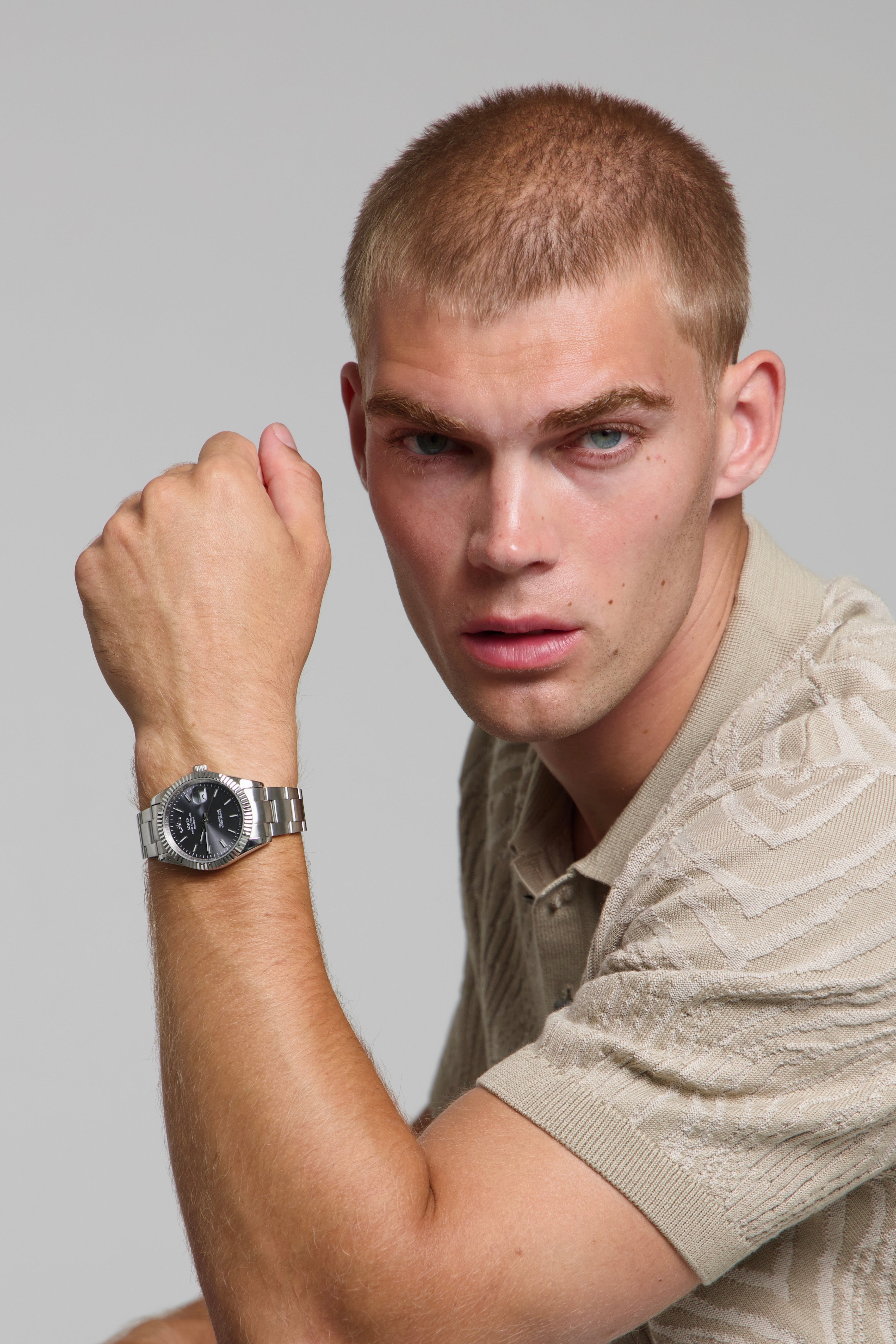 Man wearing a SOREN Momentis grey watch on a oyster bracelet, seated with his arm on a table
