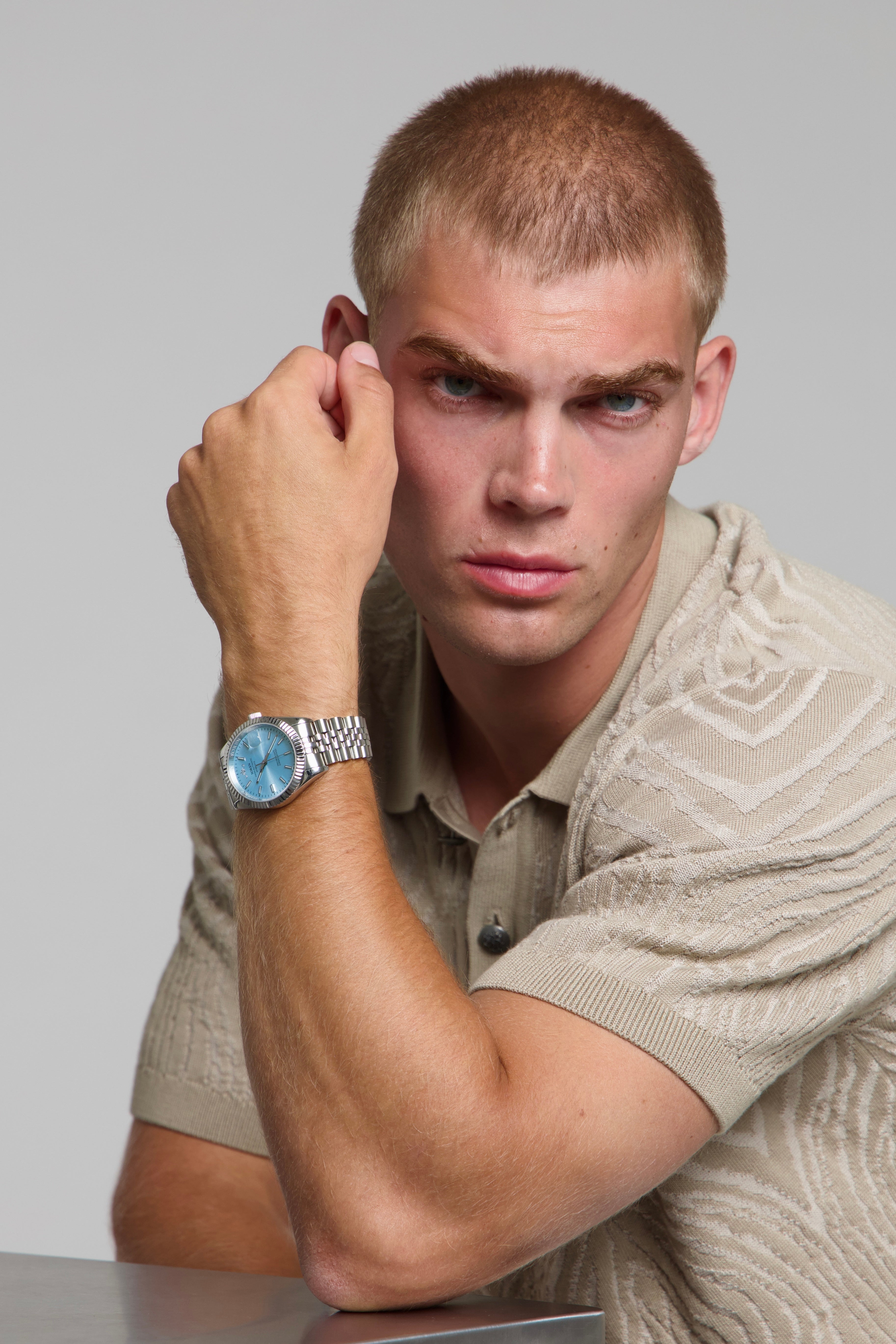 Man wearing a SOREN Momentis ice blue watch on a jubilee bracelet, seated with his arm on a table