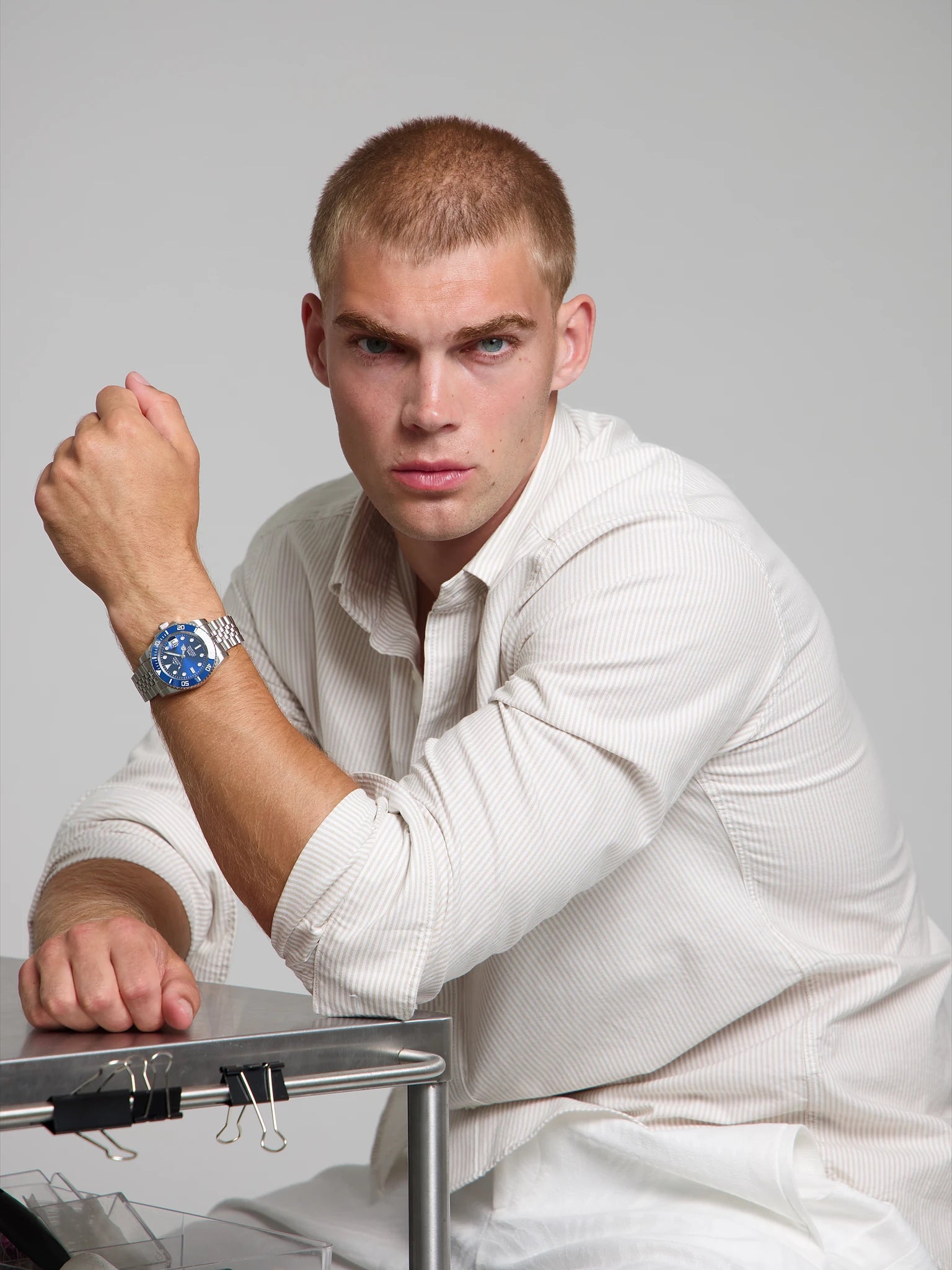 Man wearing a SOREN oceanic all blue watch on a jubilee bracelet, seated with his arm on a table