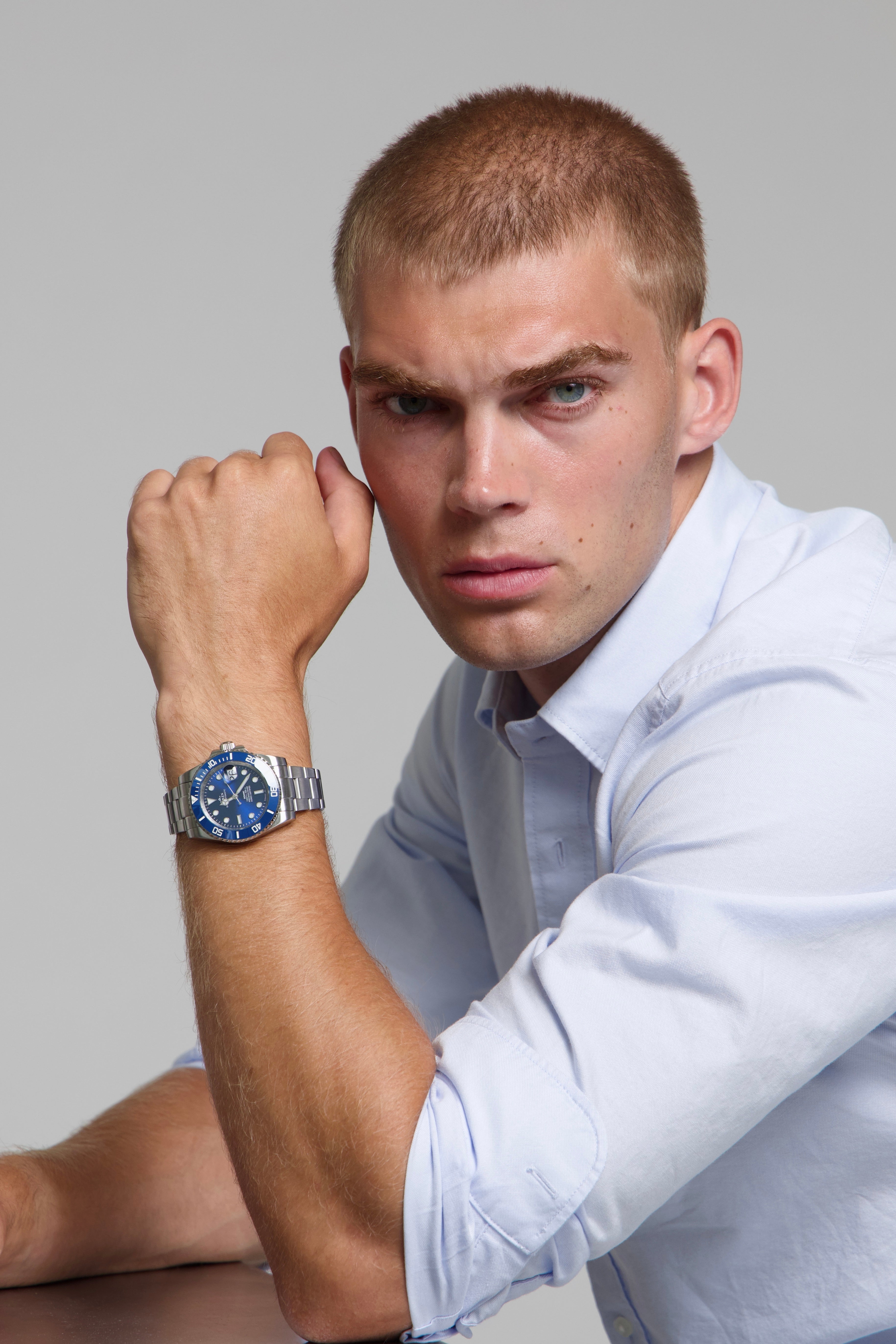 Man wearing a SOREN oceanic all blue watch on a oyster bracelet, seated with his arm on a table
