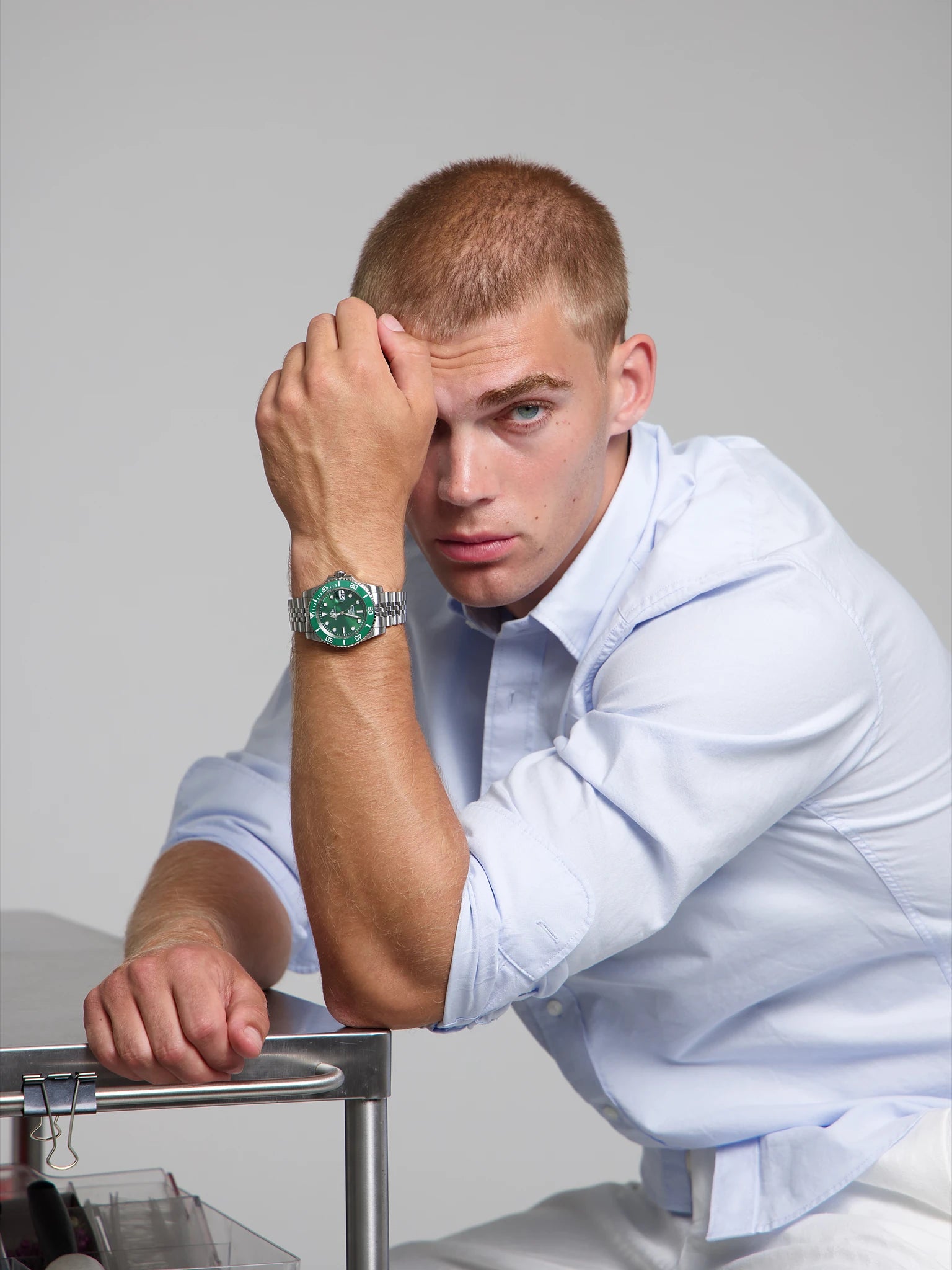 Man wearing a SOREN oceanic all green watch on a jubilee bracelet, seated with his arm on a table