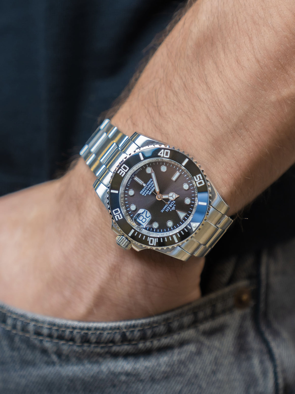 SOREN Oceanic Swiss automatic dive watch with black dial on a 3-link steel bracelet, worn on the wrist with hand in pocket