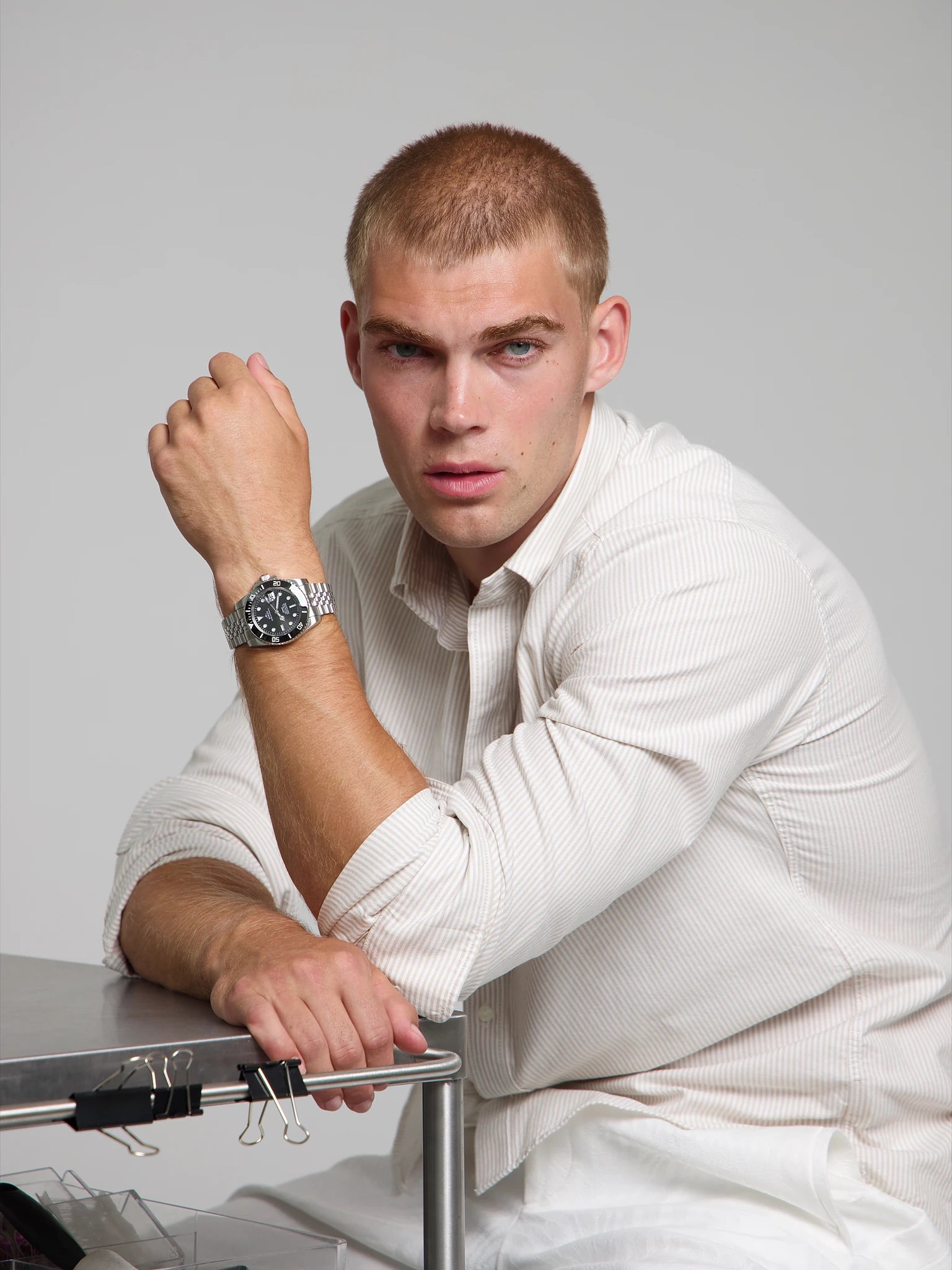 Man wearing a SOREN oceanic black watch on a jubilee bracelet, seated with his arm on a table