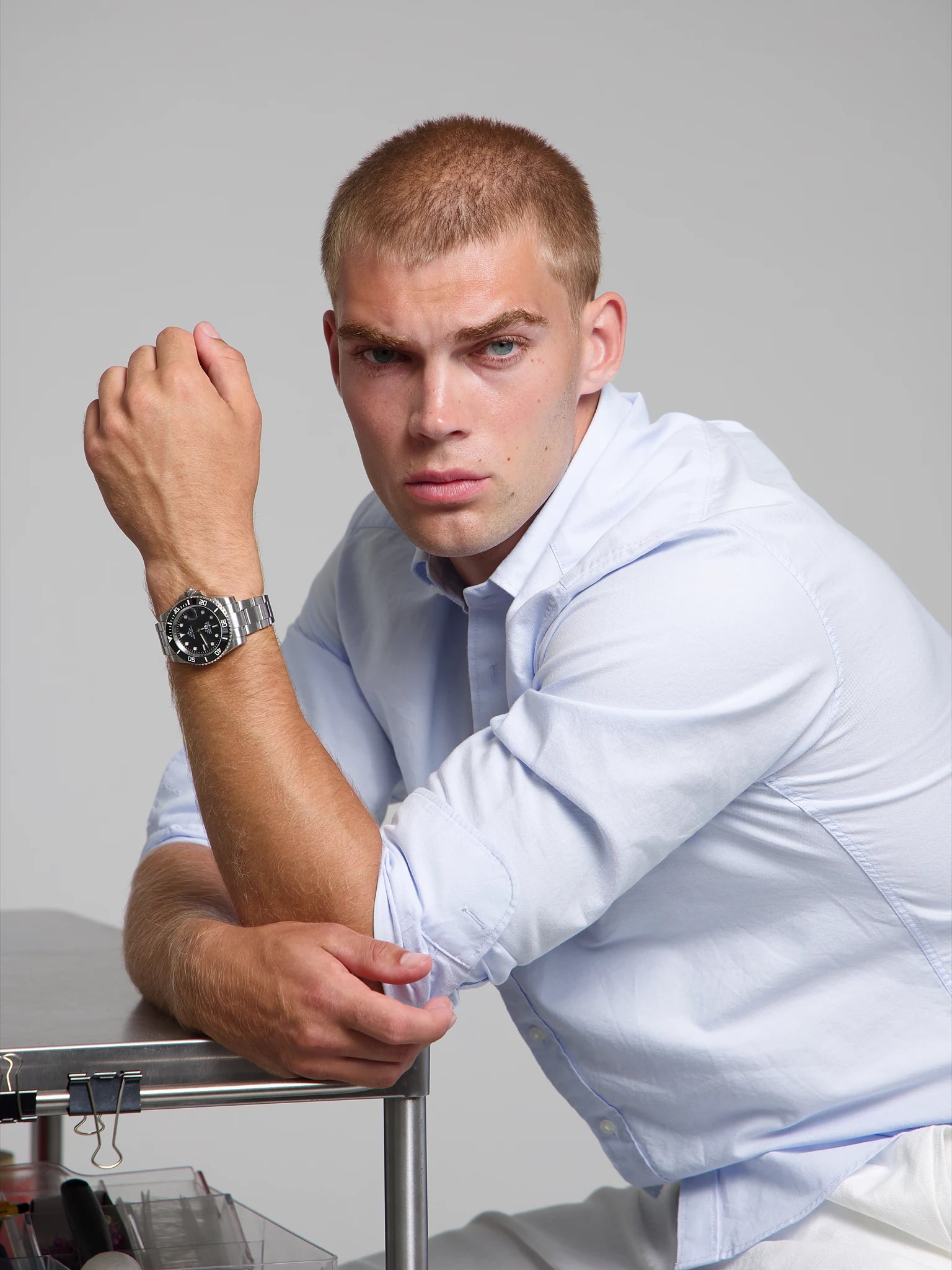 Man wearing a SOREN oceanic black watch on a oyster bracelet, seated with his arm on a table