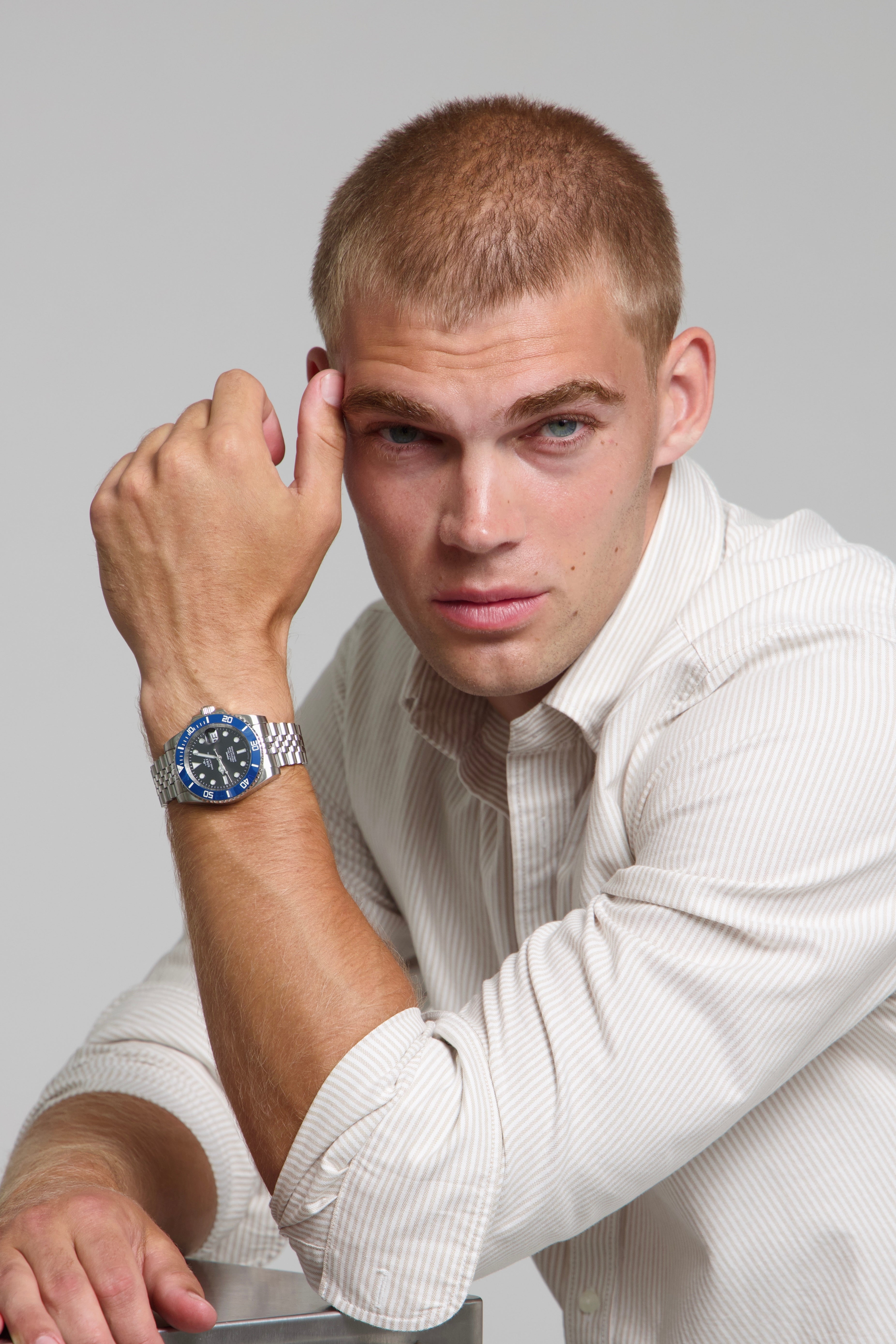 Man wearing a SOREN oceanic blue watch on a jubilee bracelet, seated with his arm on a table