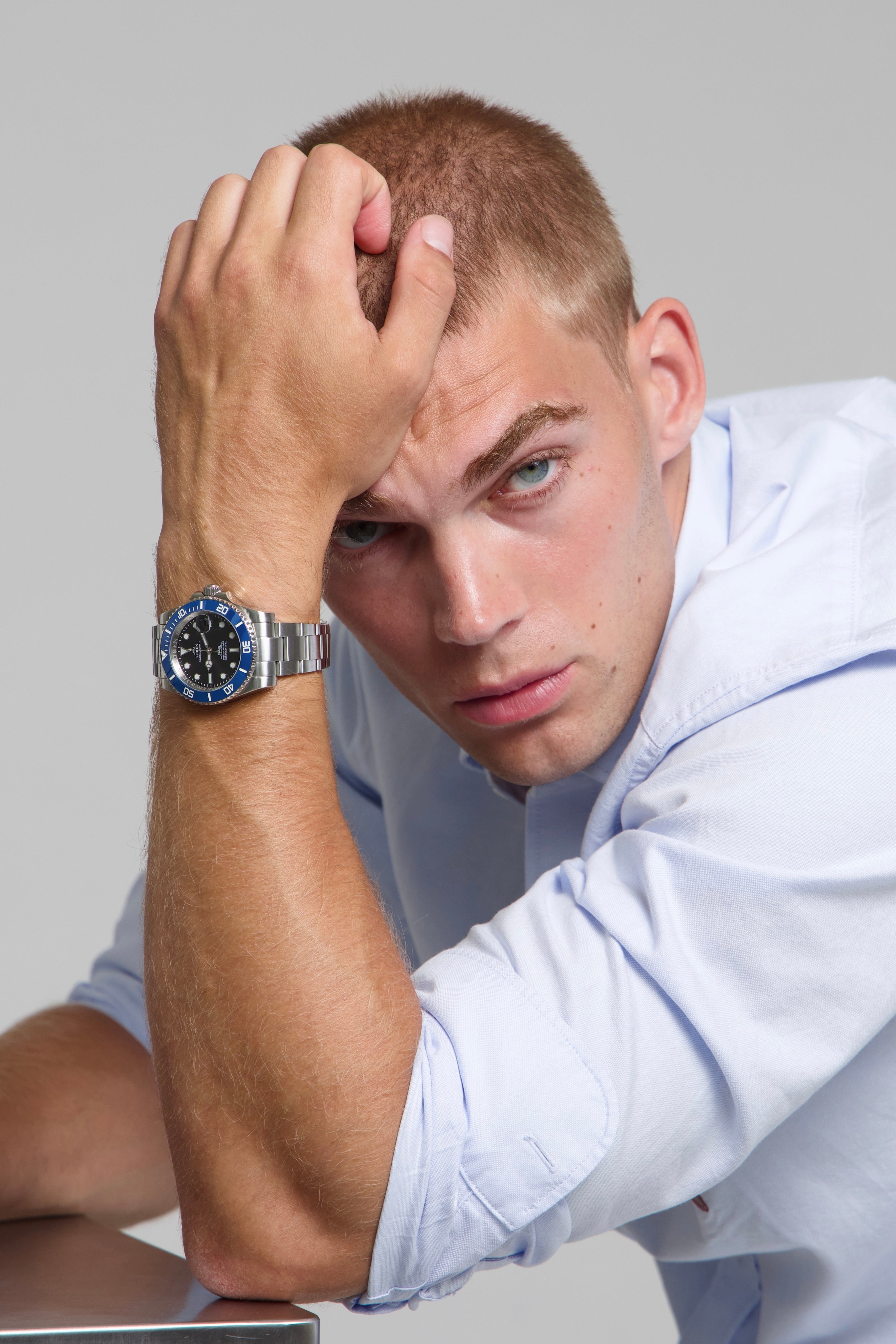 Man wearing a SOREN oceanic blue watch on a oyster bracelet, seated with his arm on a table
