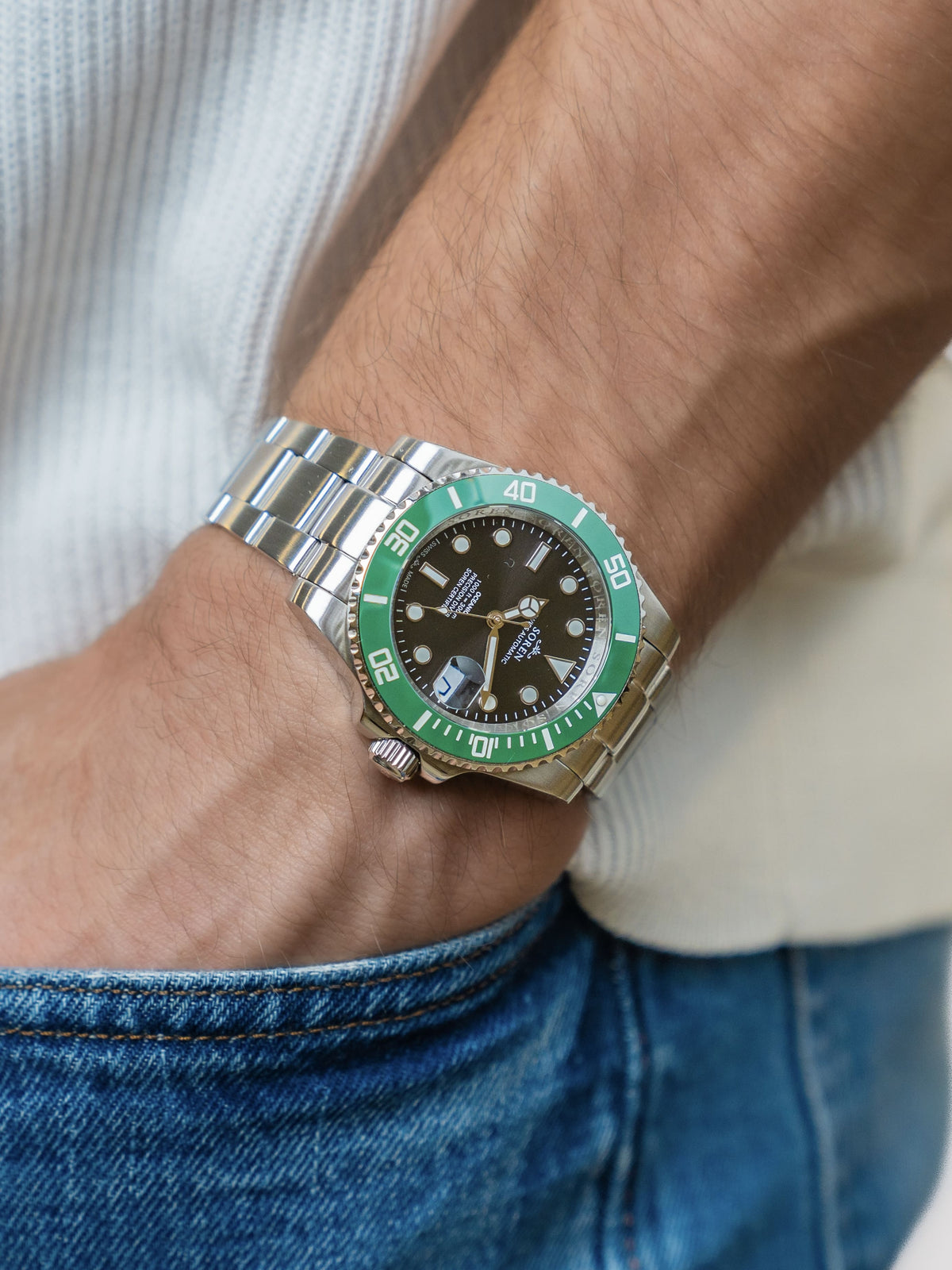 SOREN Oceanic Swiss automatic dive watch with a green bezel on a 3-link steel bracelet, worn on the wrist with hand in pocket