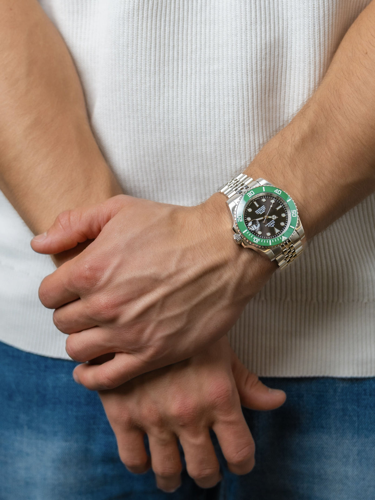 SOREN Oceanic Swiss automatic dive watch with a green bezel and black dial on a 5-link steel bracelet, shown with hands clasped together