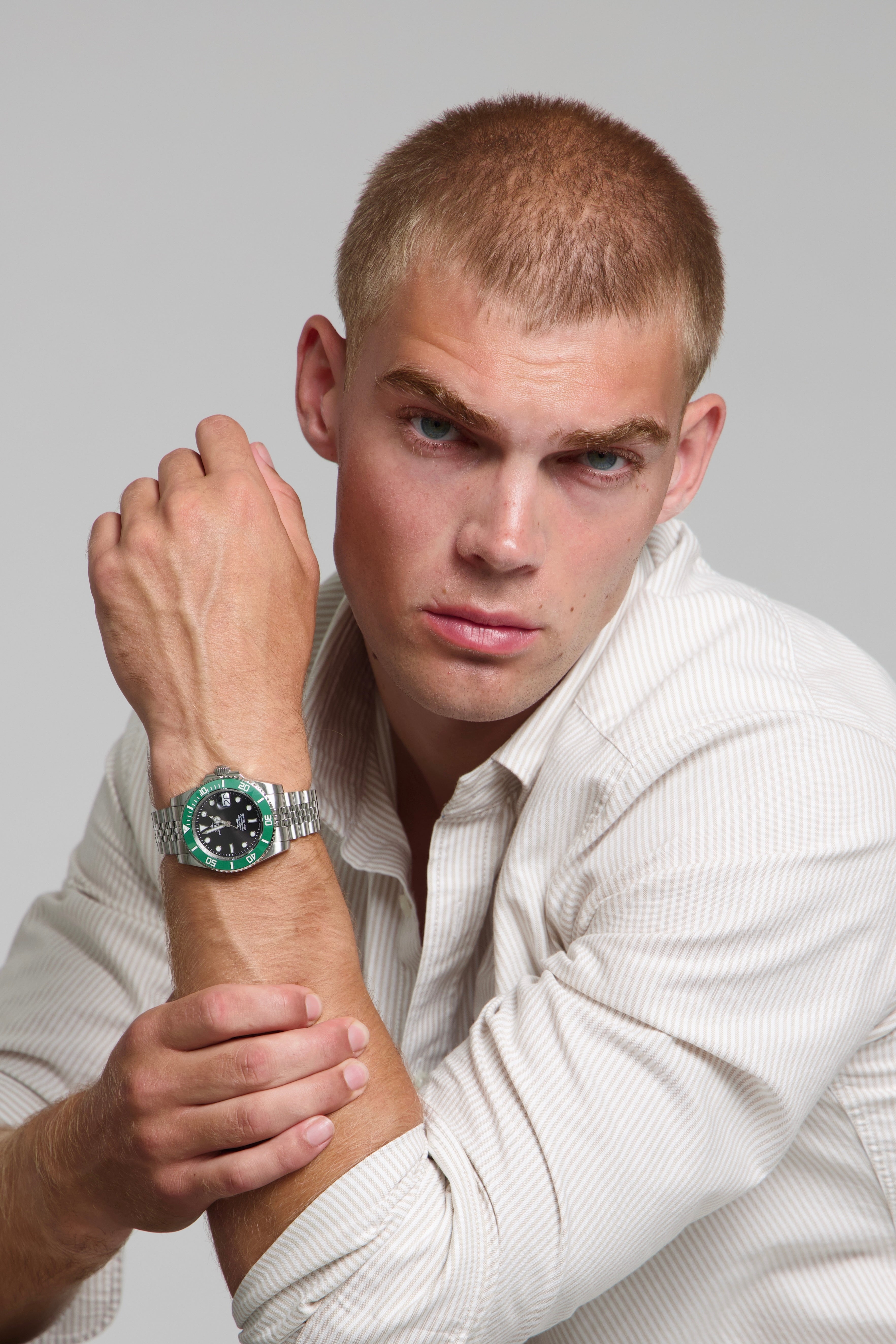 Man wearing a SOREN oceanic green watch on a jubilee bracelet, seated with his arm on a table