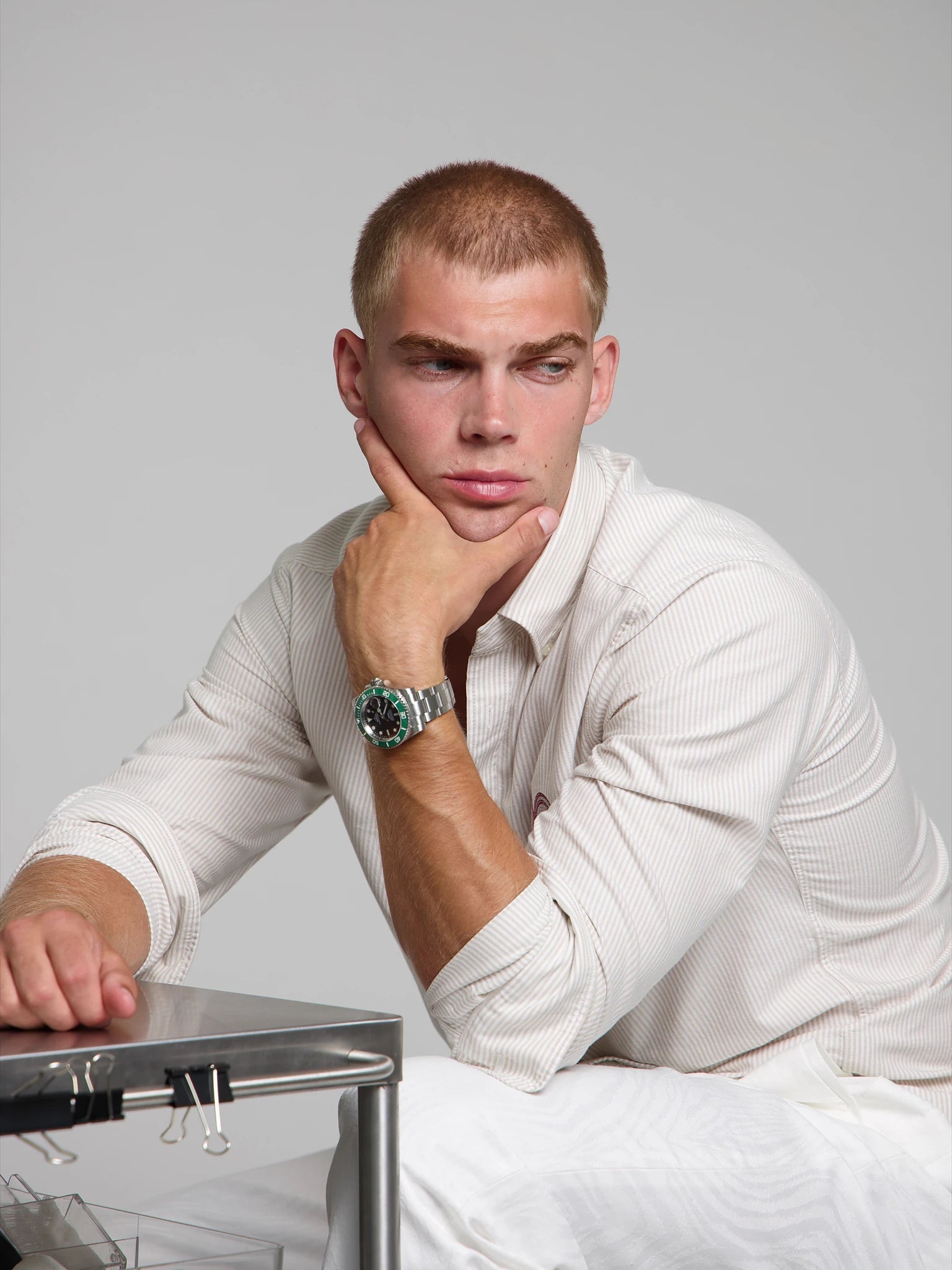 Man wearing a SOREN oceanic green watch on a oyster bracelet, seated with his arm on his leg