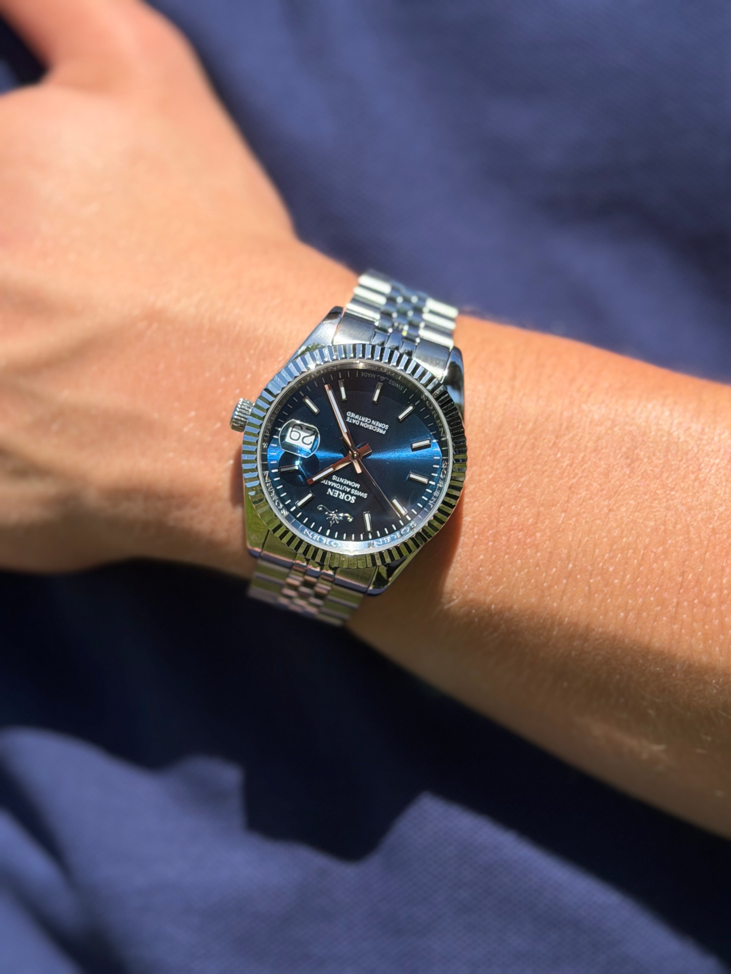 Soren Momentis Blue wrist shot close-up — blue dial, jubilee bracelet
