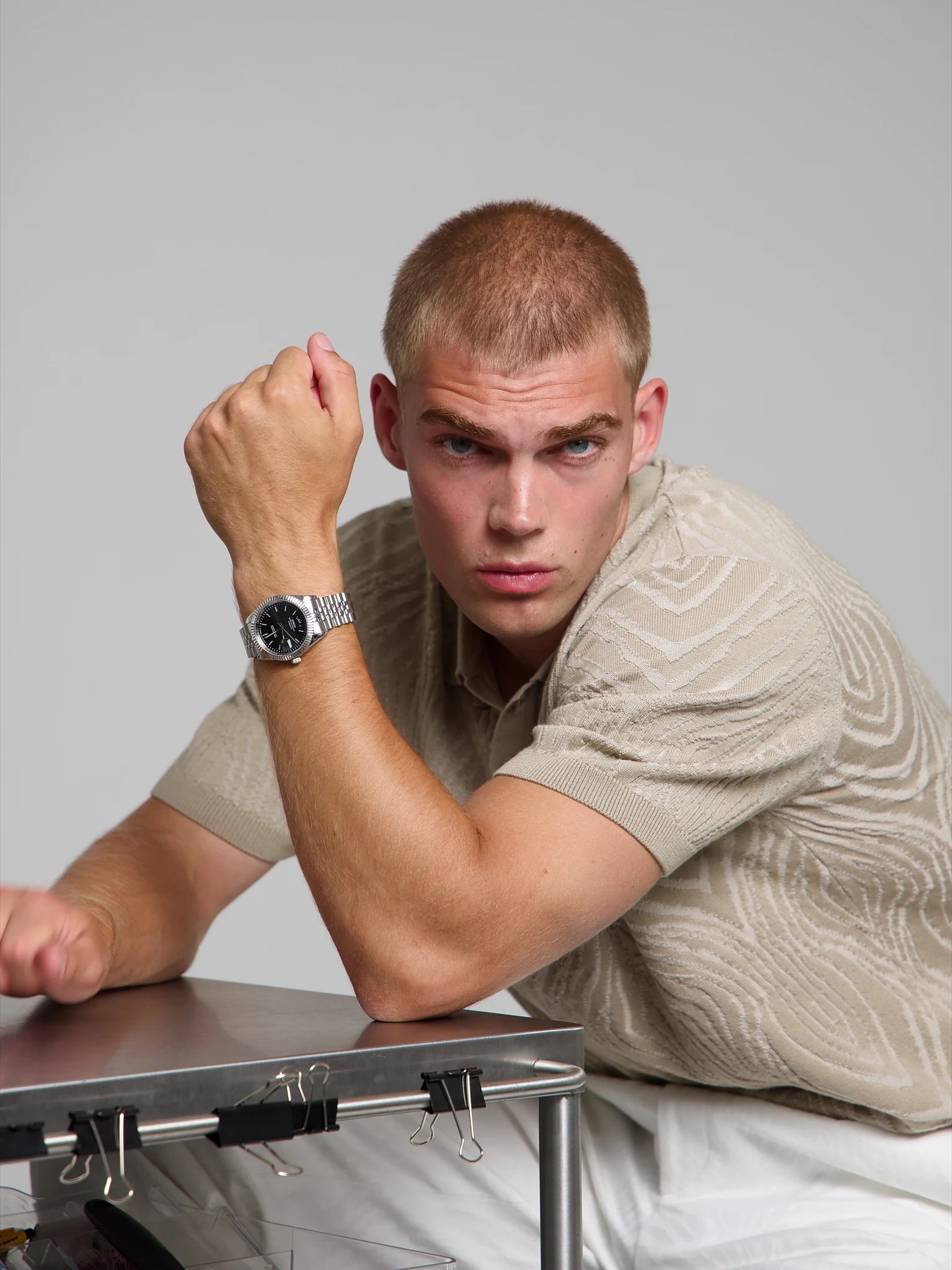Man wearing a SOREN Momentis black watch on a jubilee bracelet, seated with his arm on a table
