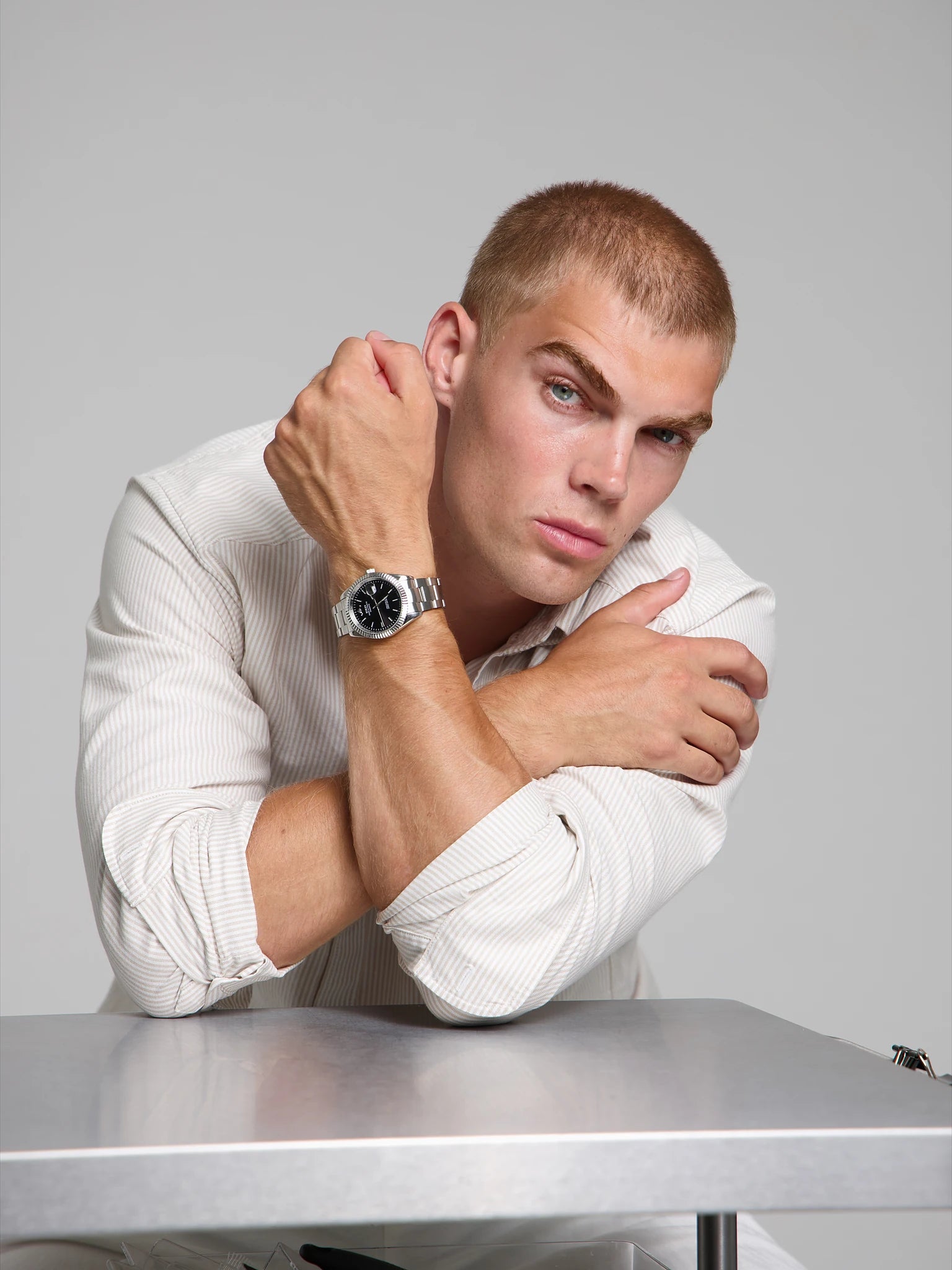 Man wearing a SOREN Momentis black watch on a oyster bracelet, seated with his arms on a table
