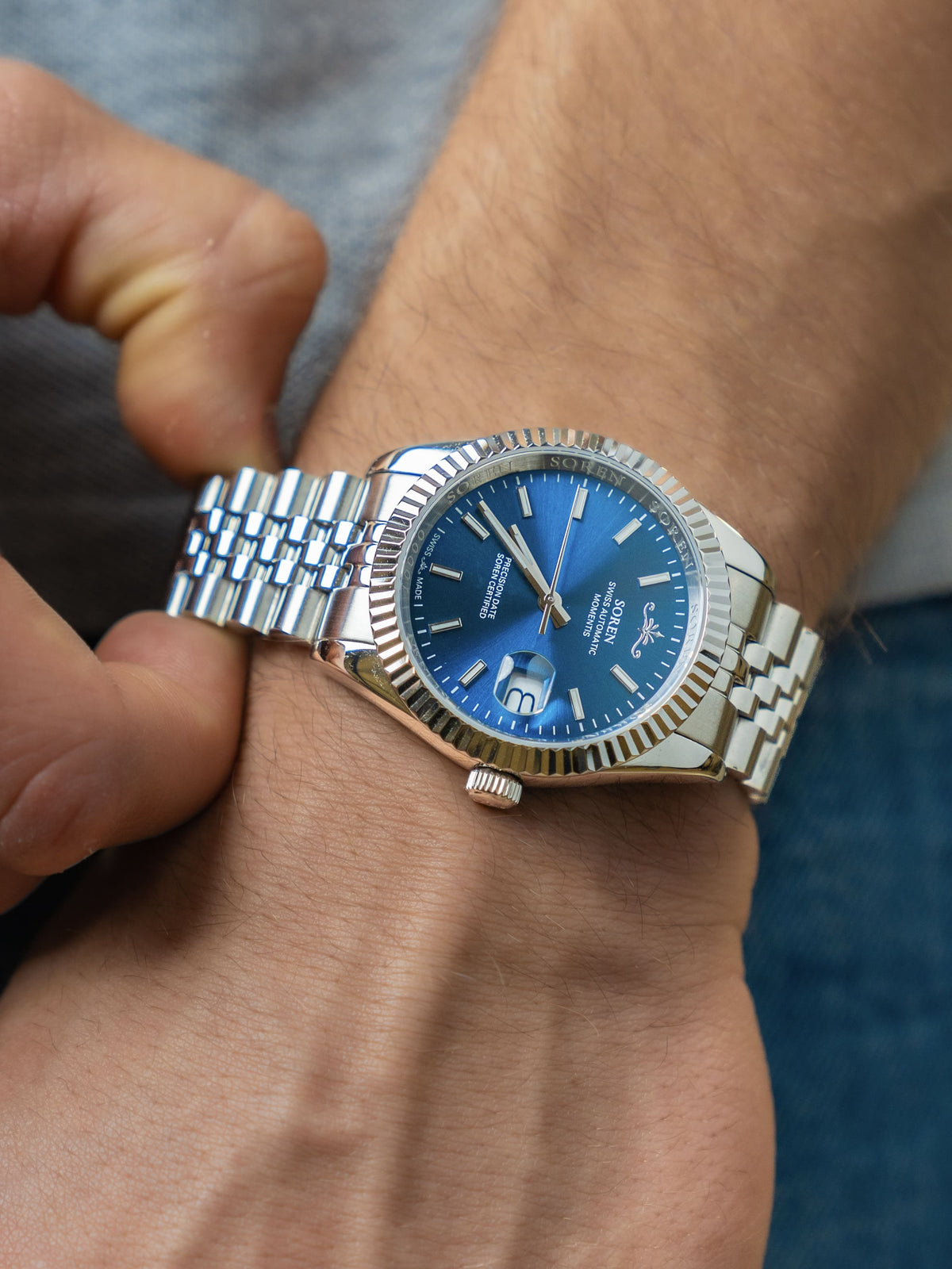 Man adjusting the 5-link steel bracelet of the SOREN Momentis Swiss automatic watch with blue dial
