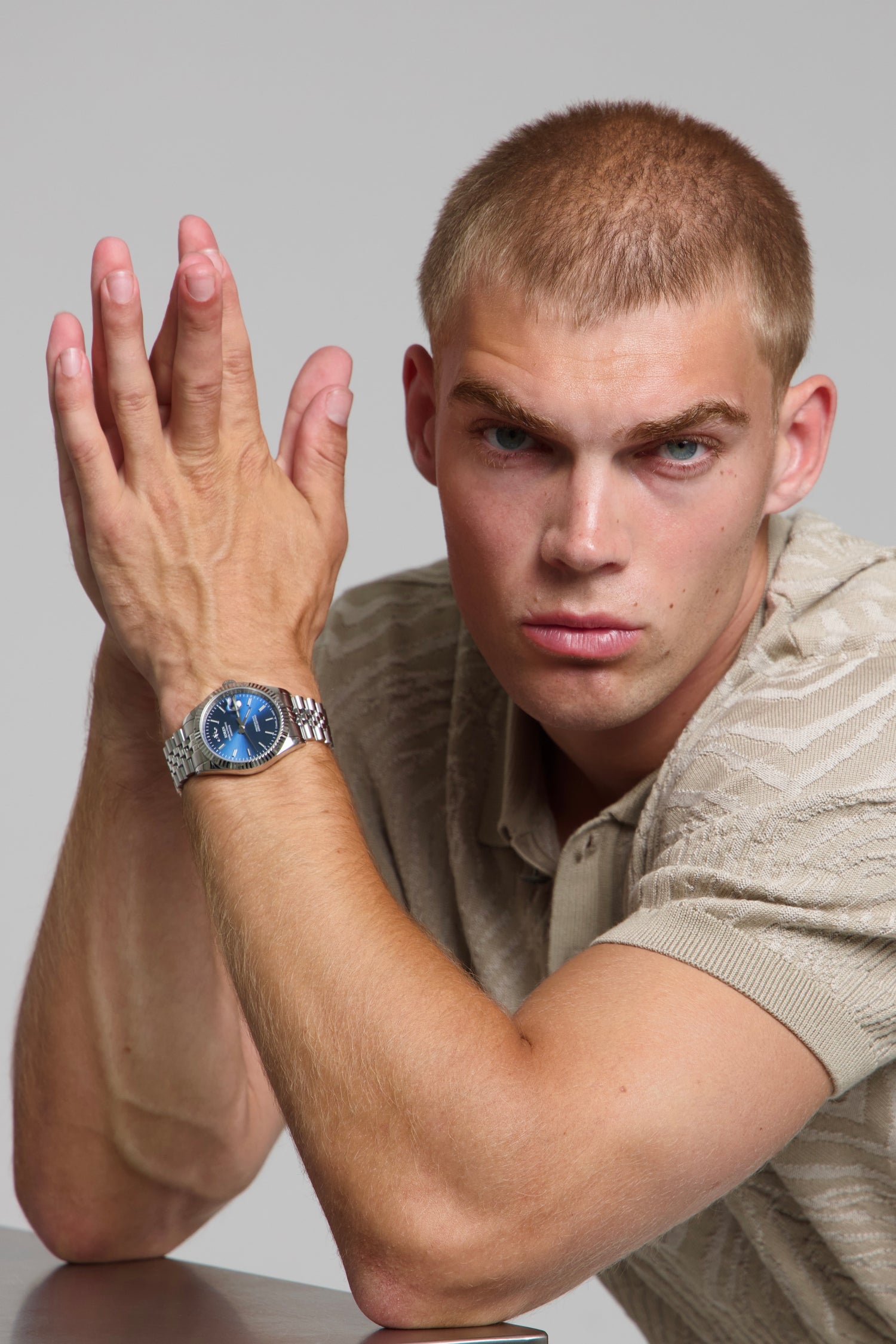 Man wearing a SOREN Momentis blue watch on a jubilee bracelet, seated with his arm on a table
