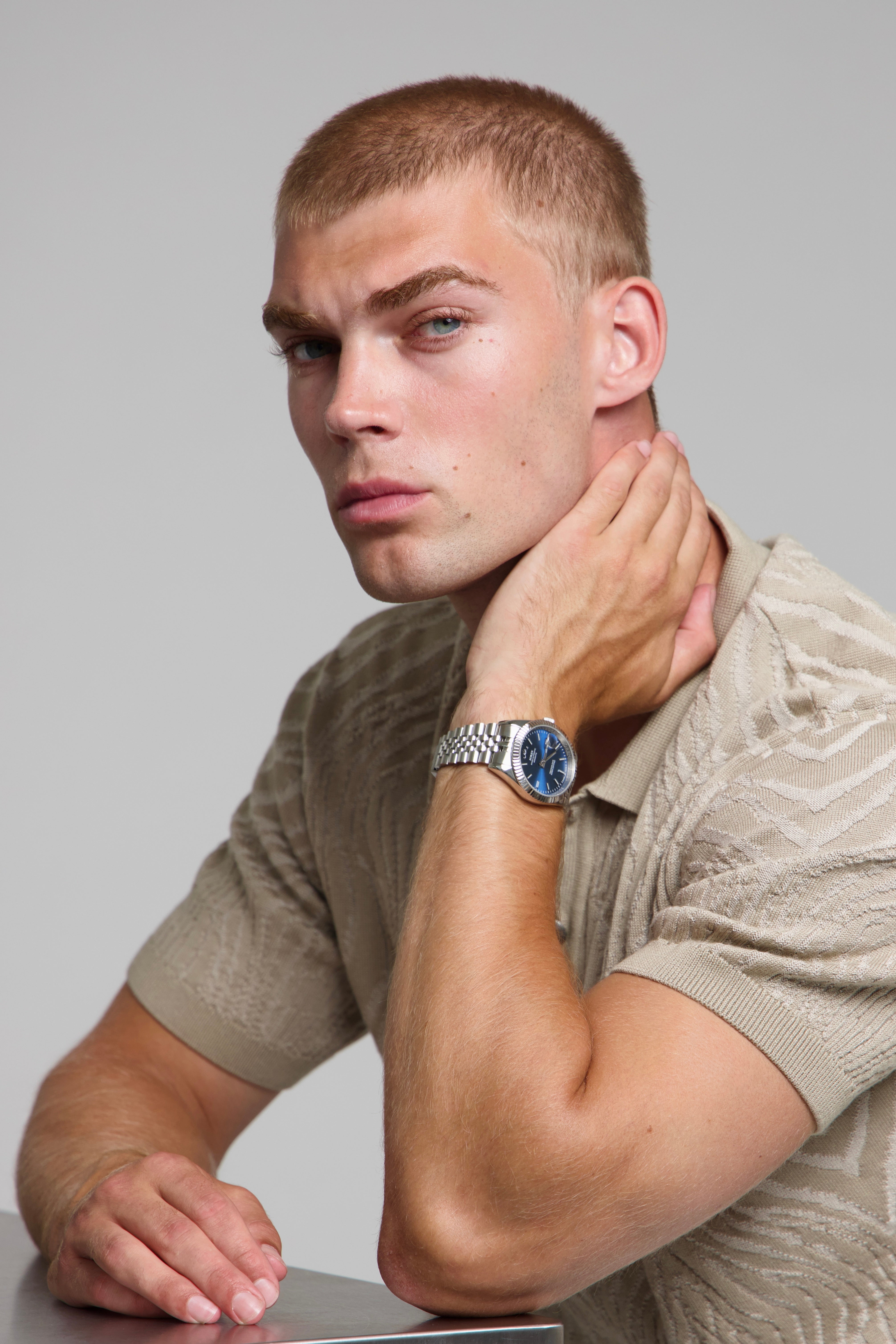 Model wearing a SOREN Momentis blue watch on a jubilee bracelet, seated
