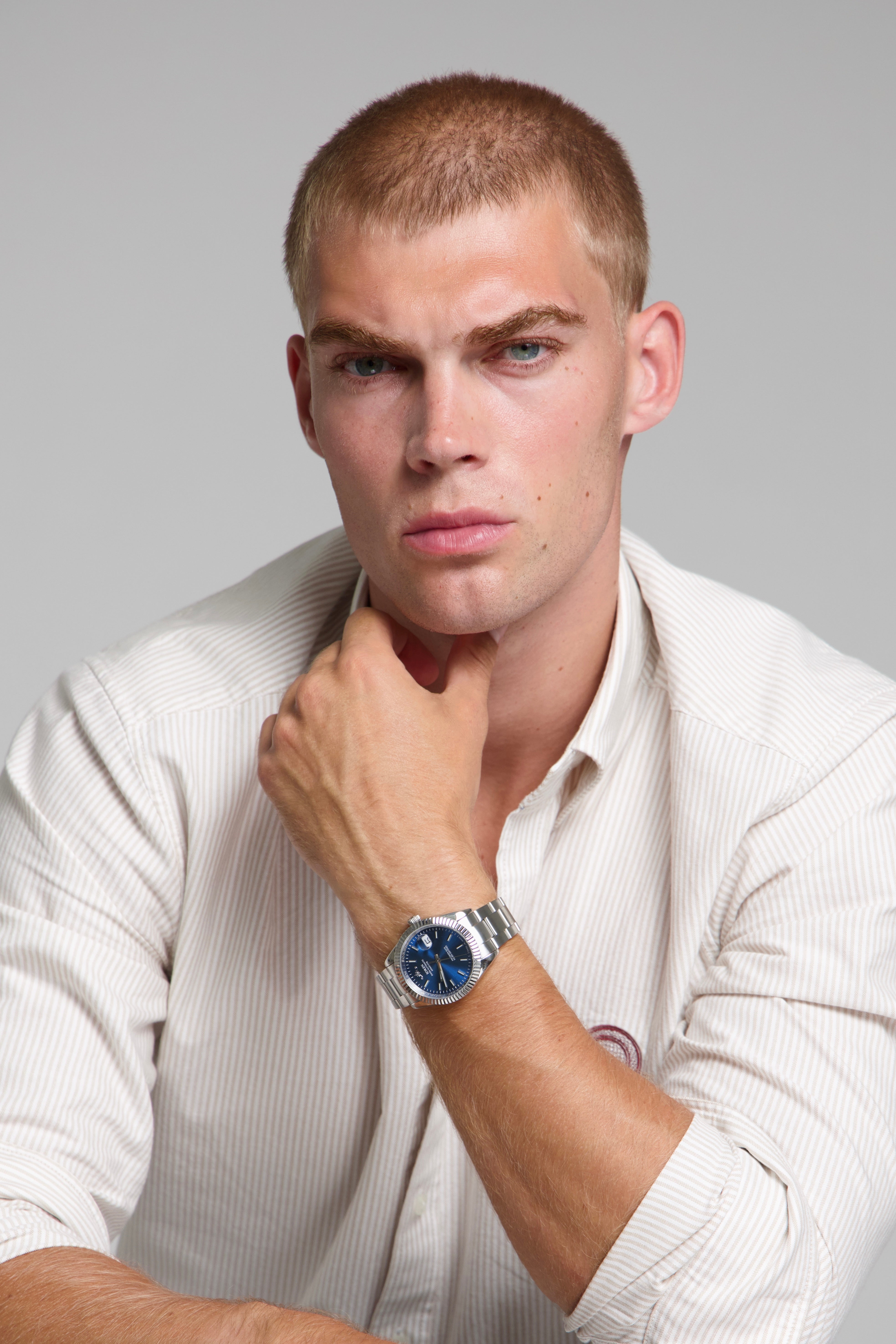 Man wearing a SOREN Momentis blue watch on a oyster bracelet, seated with his arm on a table
