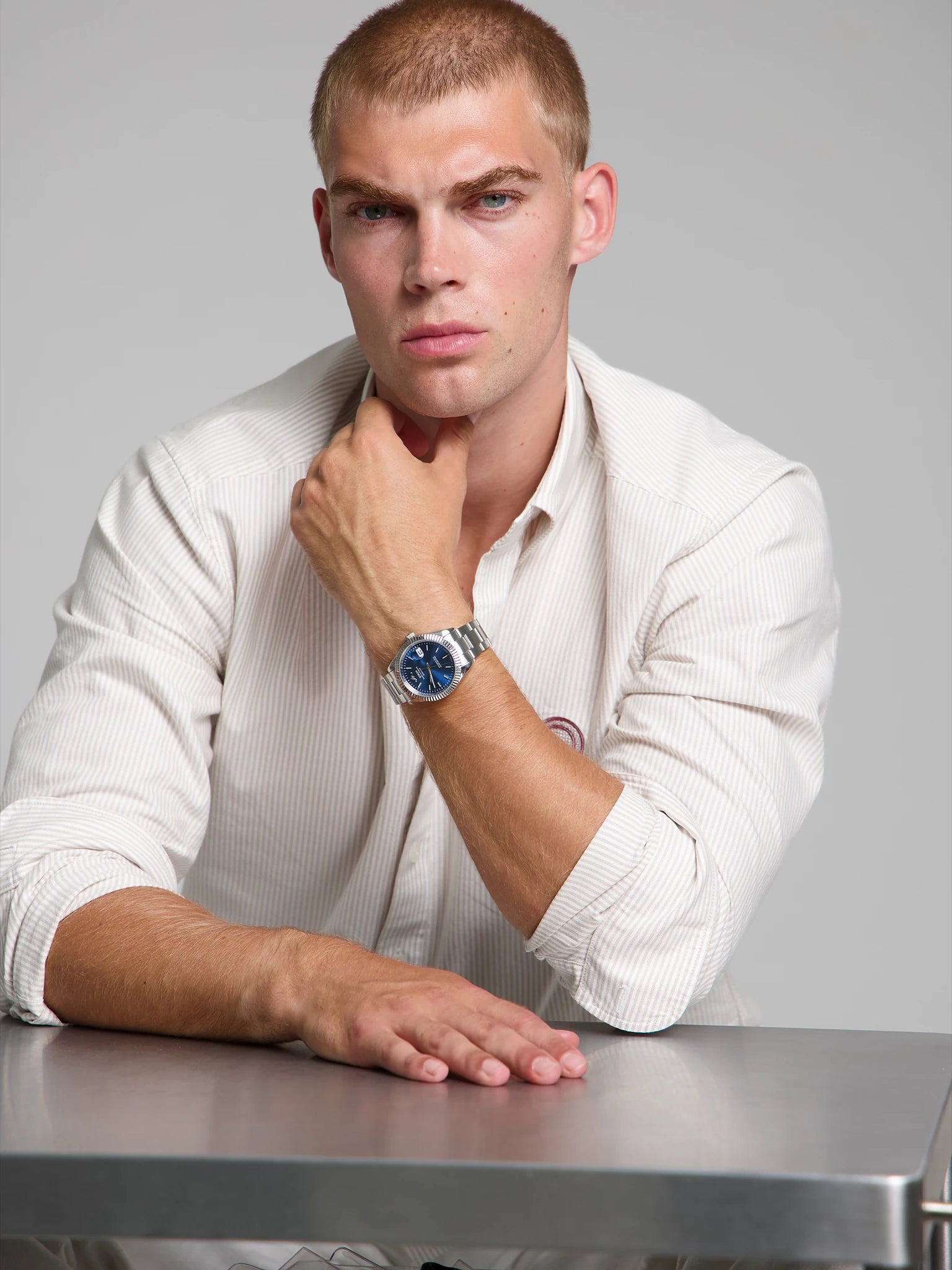 Man wearing a SOREN Momentis blue watch on a oyster bracelet, seated with his arm on a table

