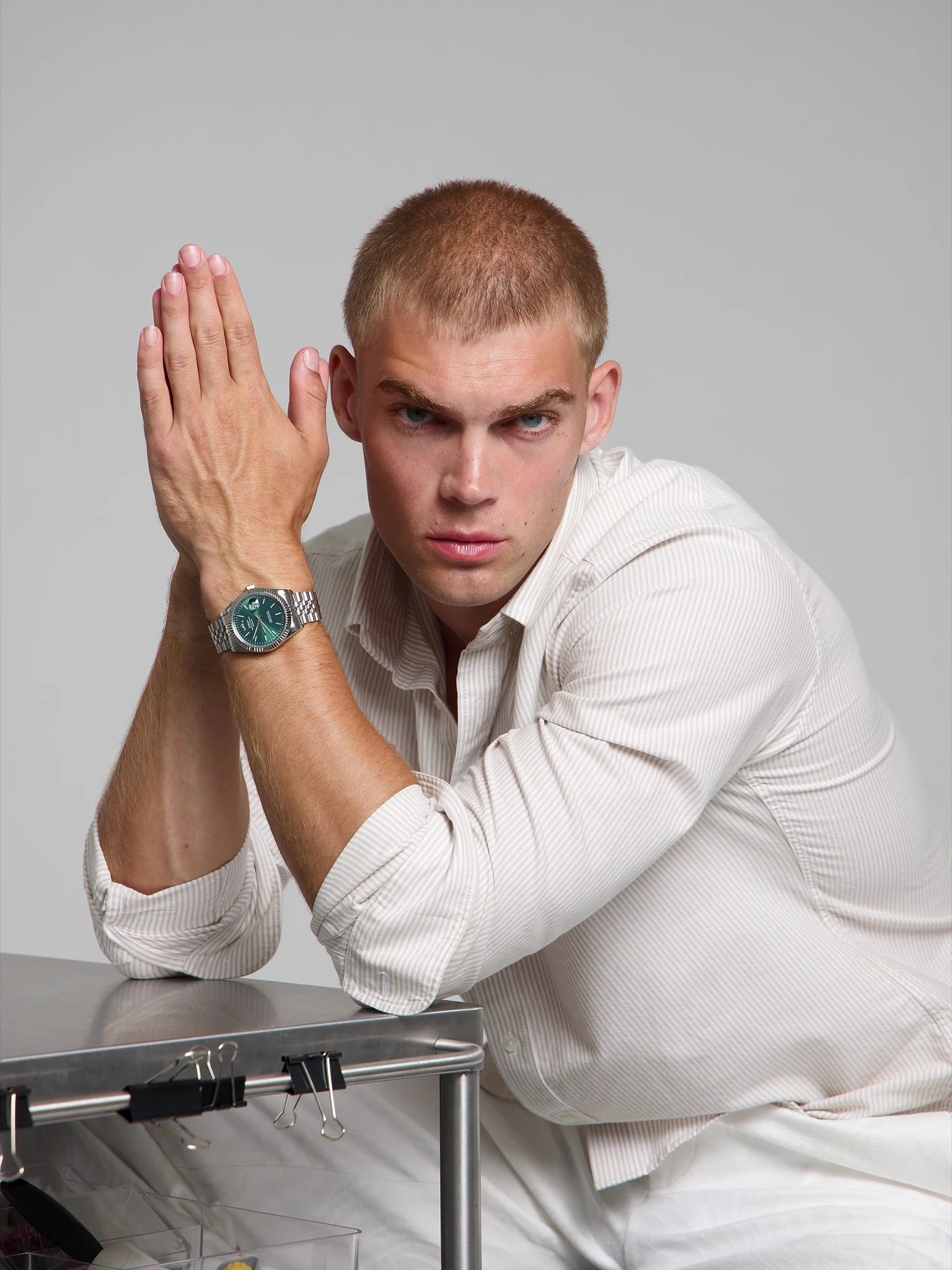 Man wearing a SOREN Momentis green watch on a jubilee bracelet, seated with his arms on a table
