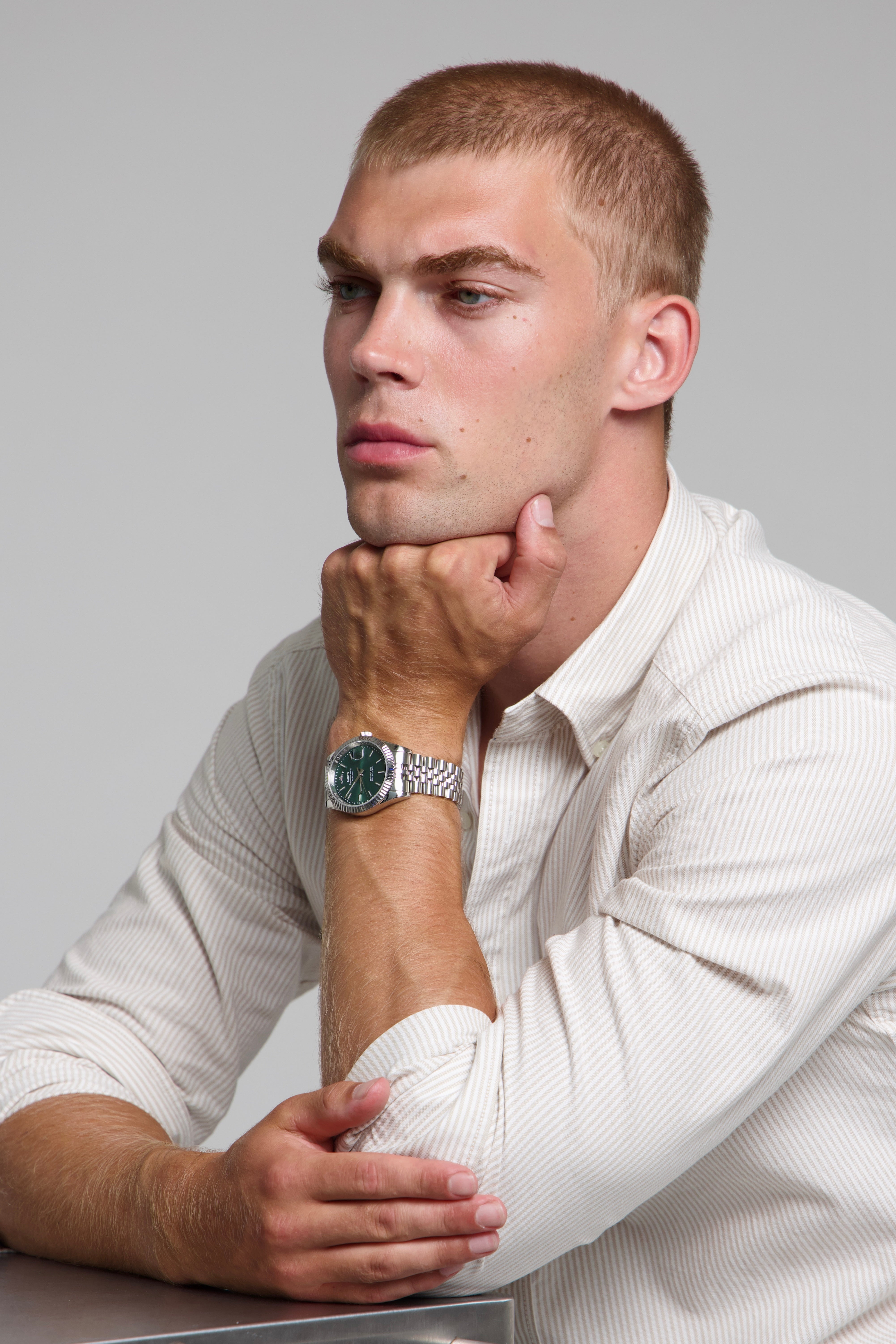 Model wearing a SOREN Momentis green watch on a jubilee bracelet, seated
