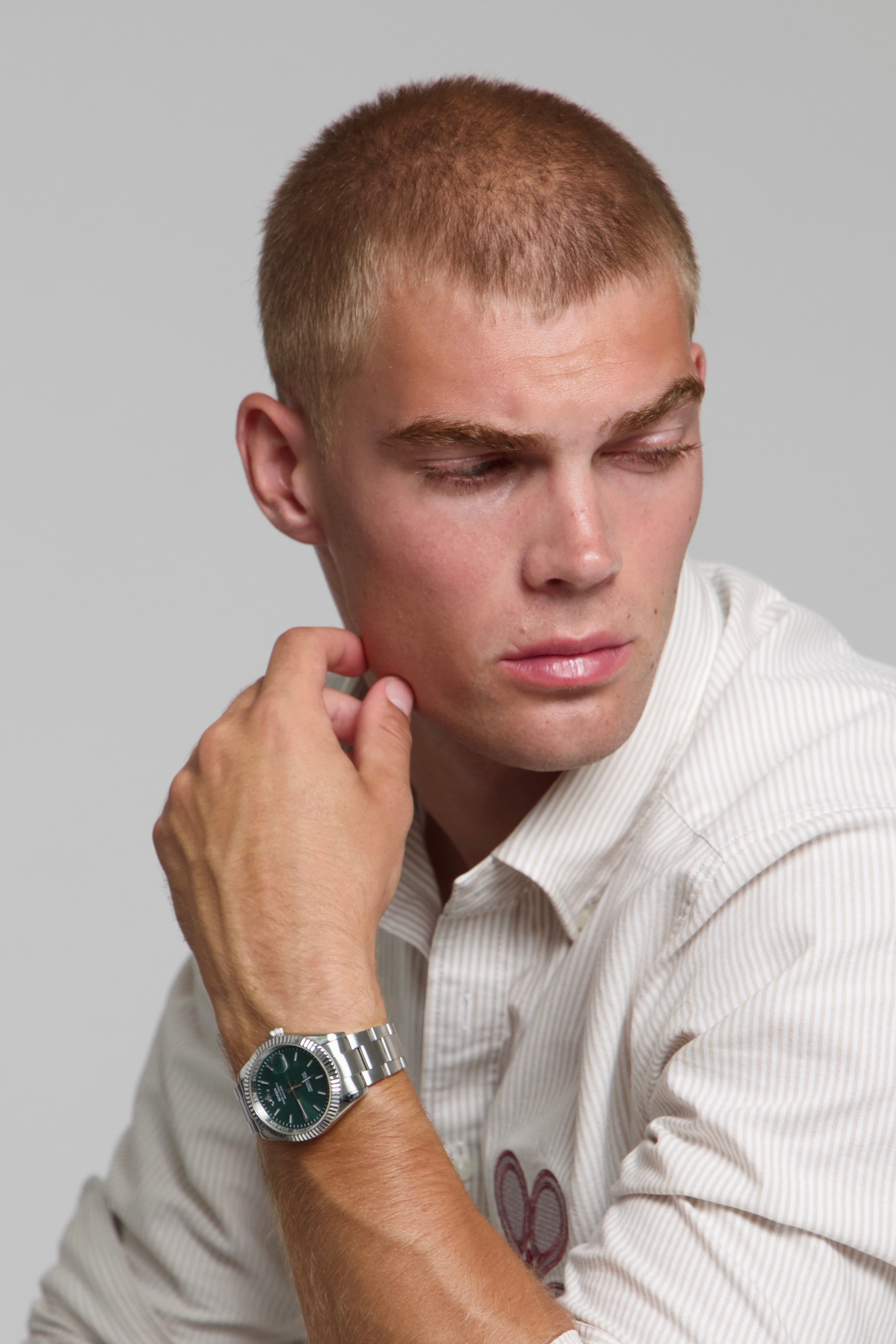 Man wearing a SOREN Momentis green watch on a oyster bracelet, seated with his arm on his leg
