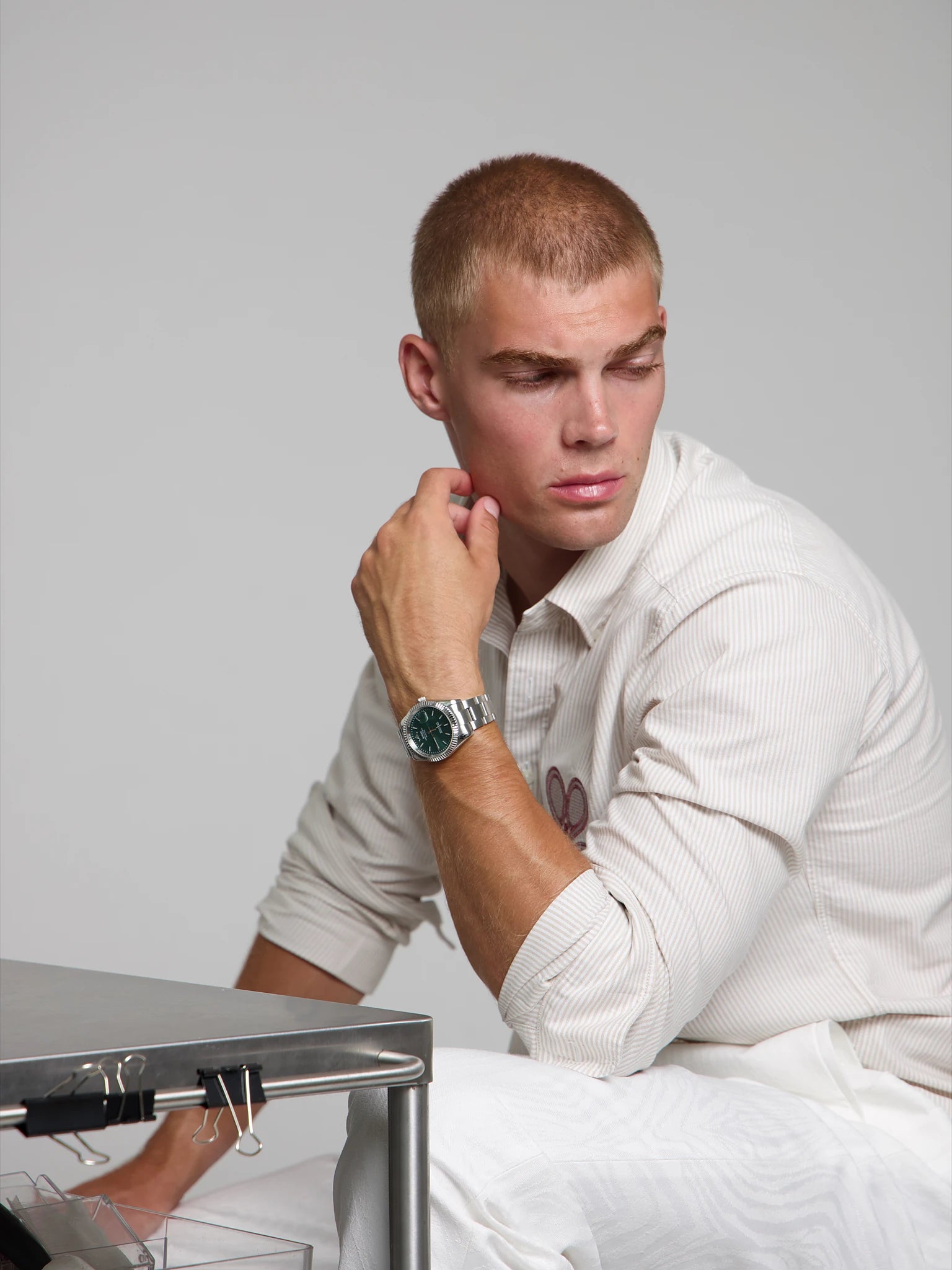 Man wearing a SOREN Momentis green watch on a oyster bracelet, seated with his arm on his leg
