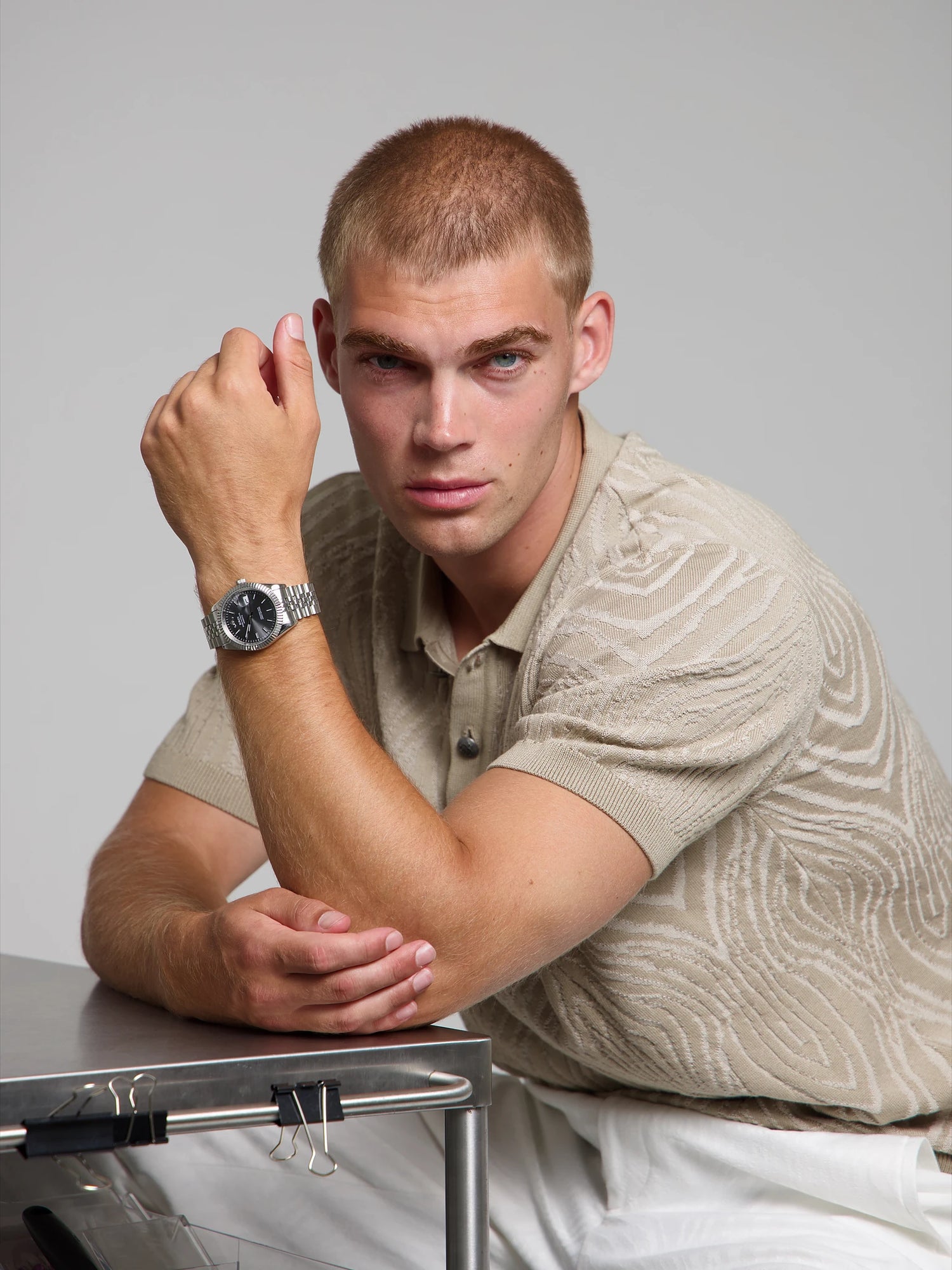 Man wearing a SOREN Momentis grey watch on a jubilee bracelet, seated with his arm on a table
