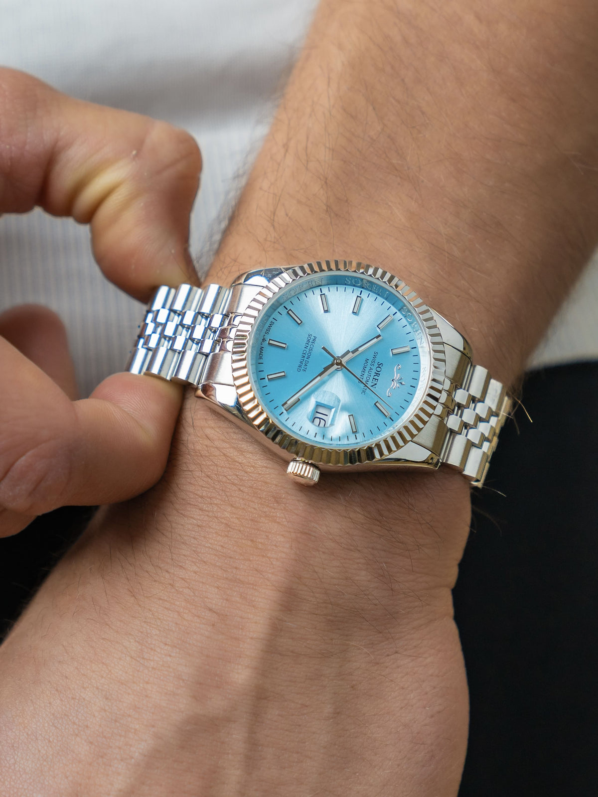 Man adjusting the 5-link steel bracelet of the SOREN Momentis Swiss automatic watch with ice blue dial
