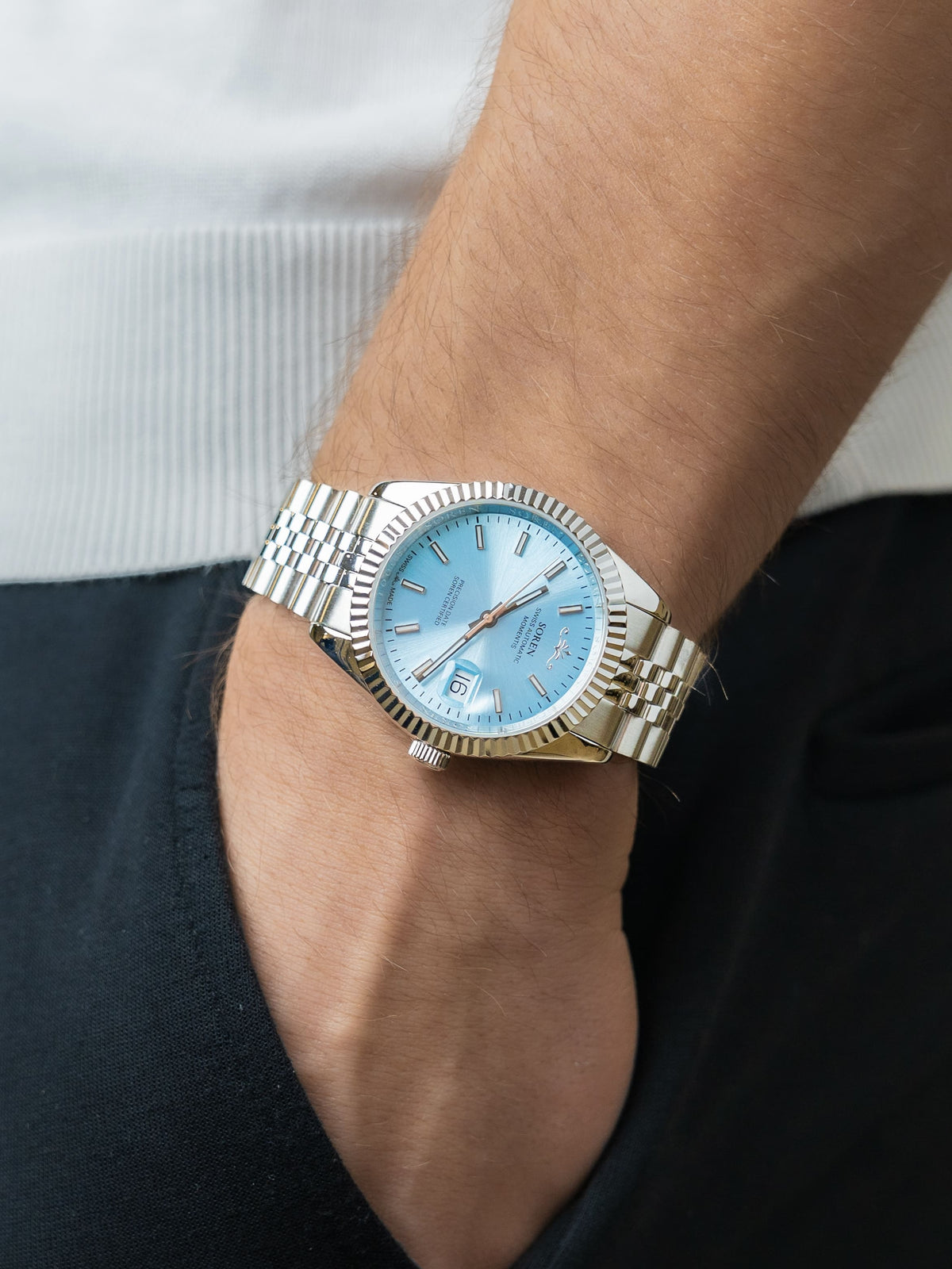 SOREN Momentis Swiss automatic watch with ice blue dial on a 5-link steel bracelet, worn on the wrist with hand in pocket
