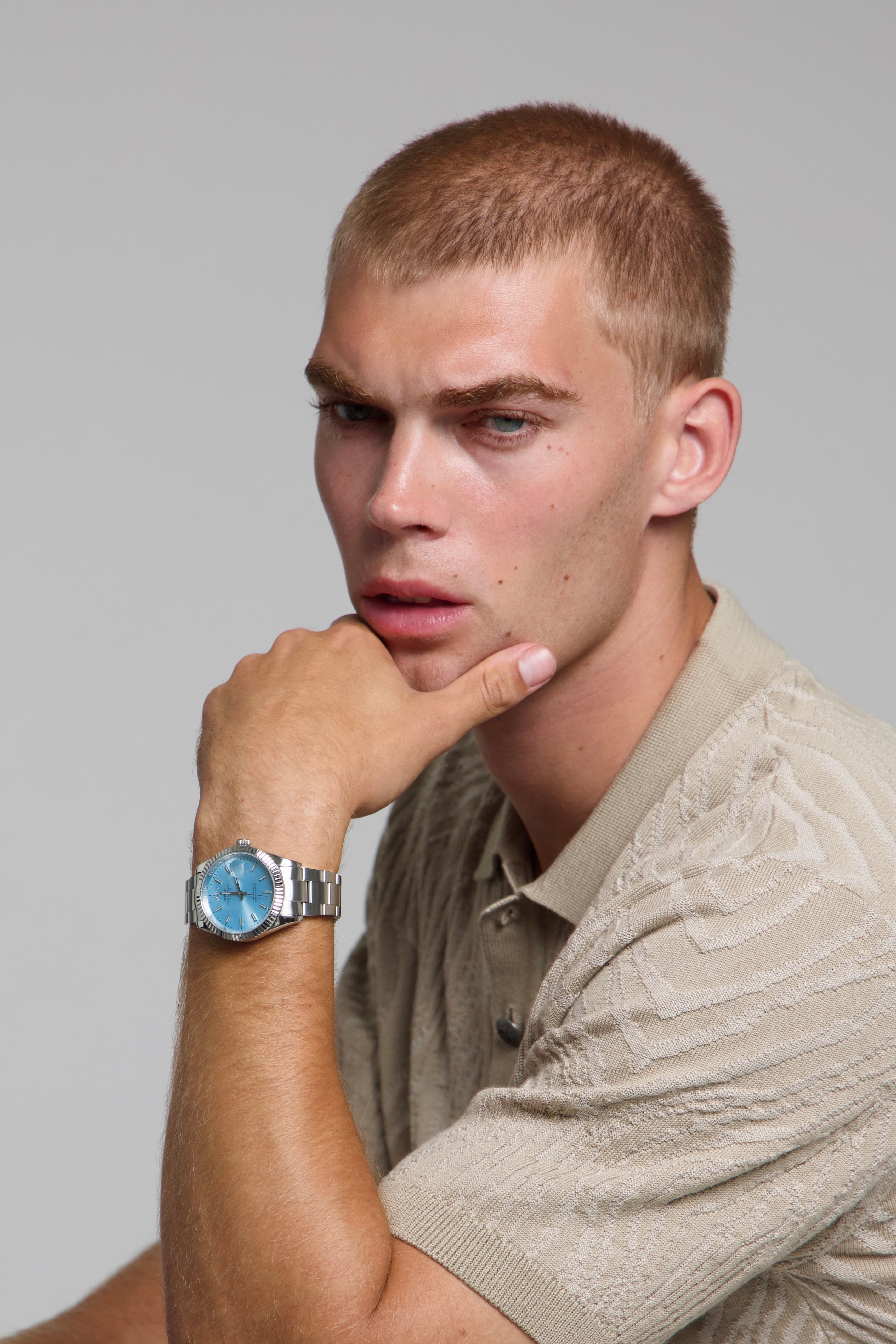 Man wearing a SOREN Momentis ice blue watch on a oyster bracelet, seated with his arm on a table
