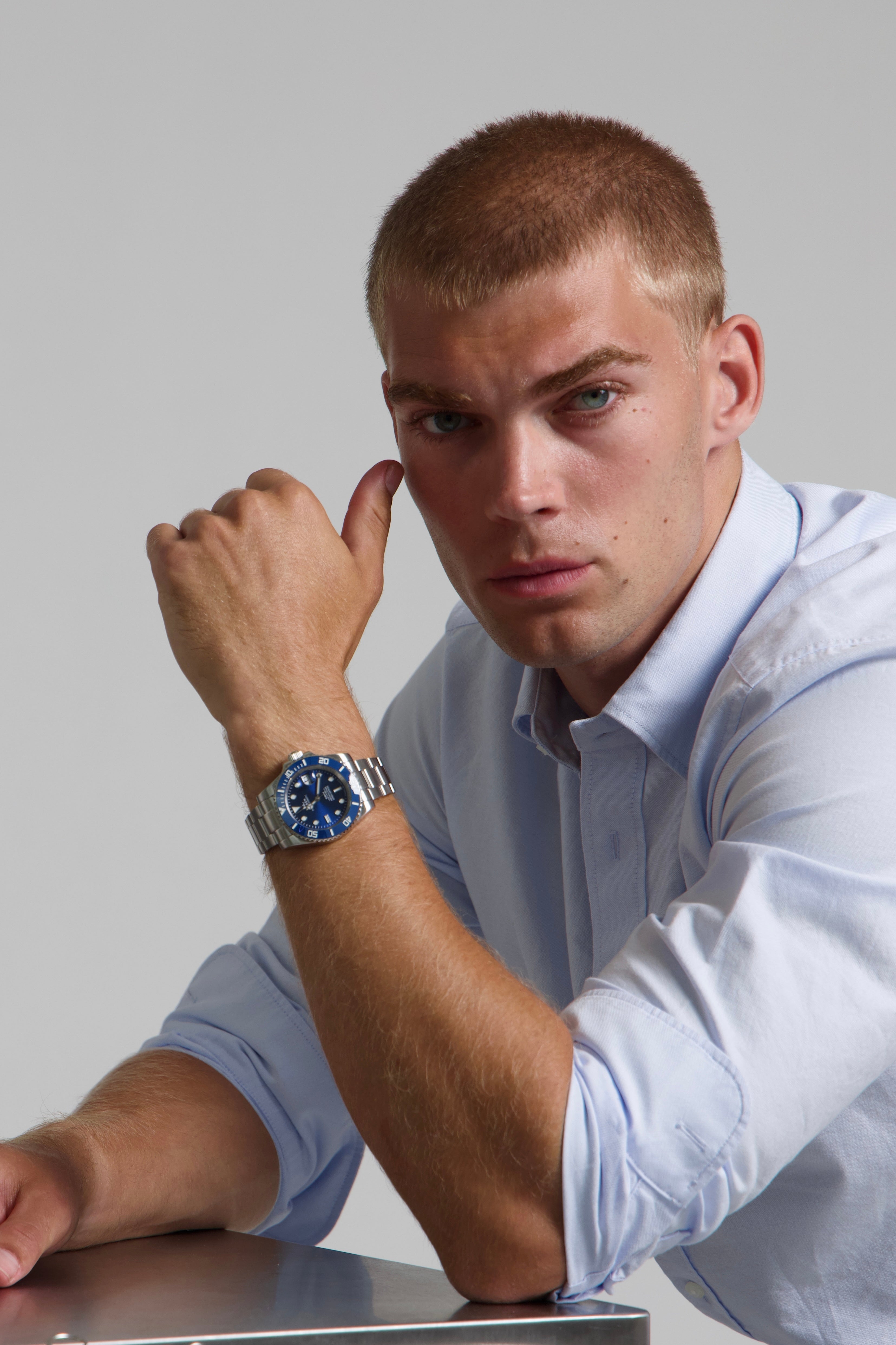 Model wearing a SOREN oceanic all blue watch on a oyster bracelet, seated
