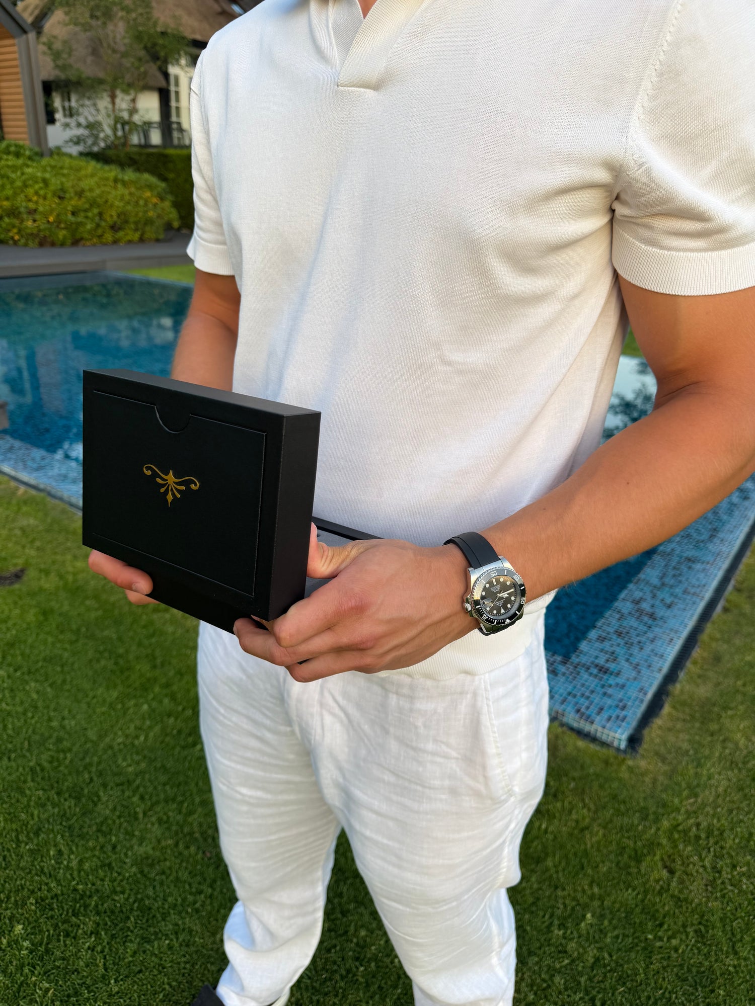 Man by a pool holding a SOREN watch box, wearing a SOREN Oceanic black dive watch