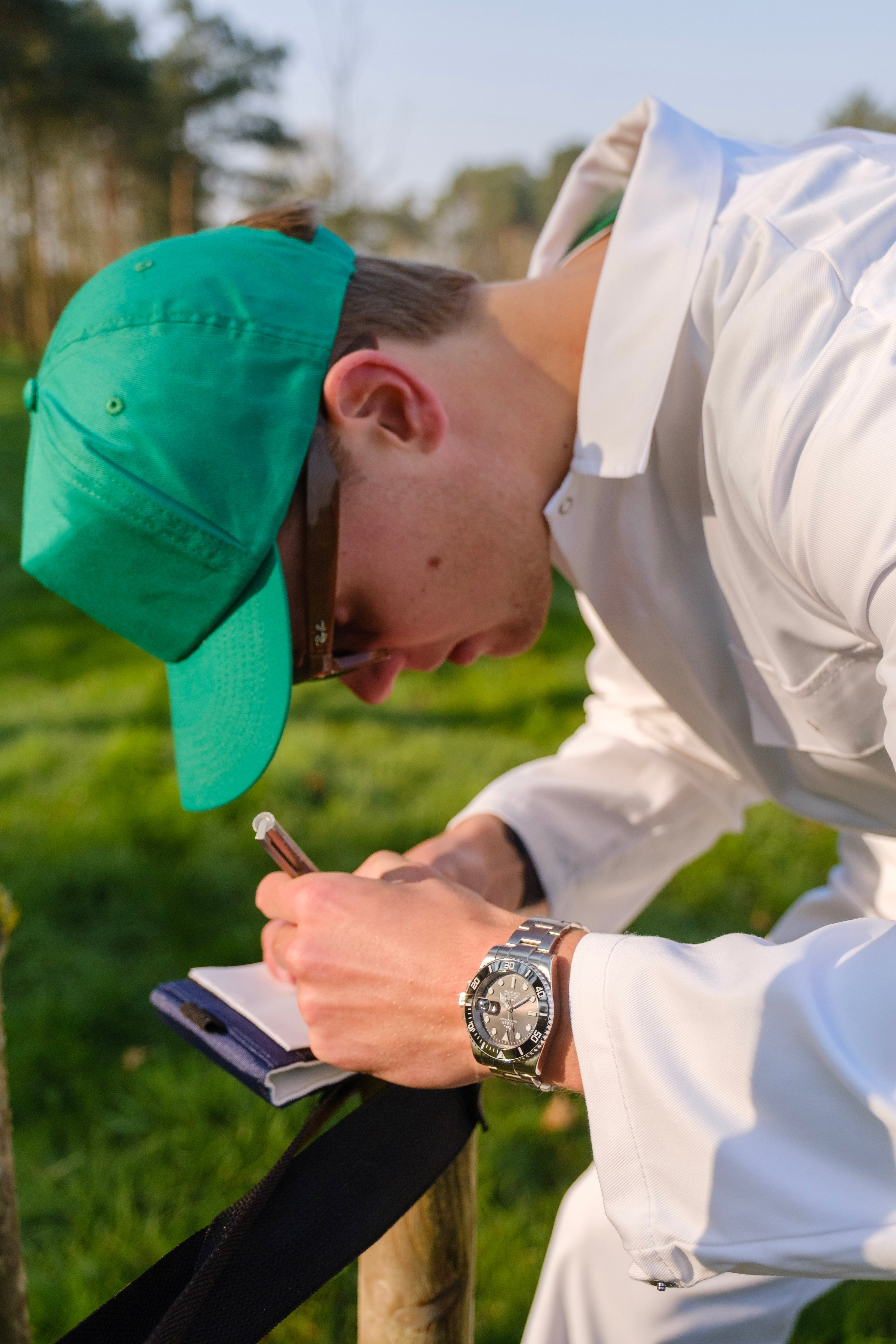 Man writing in a notebook outdoors, wearing a SOREN Oceanic dive watch on an Oyster bracelet