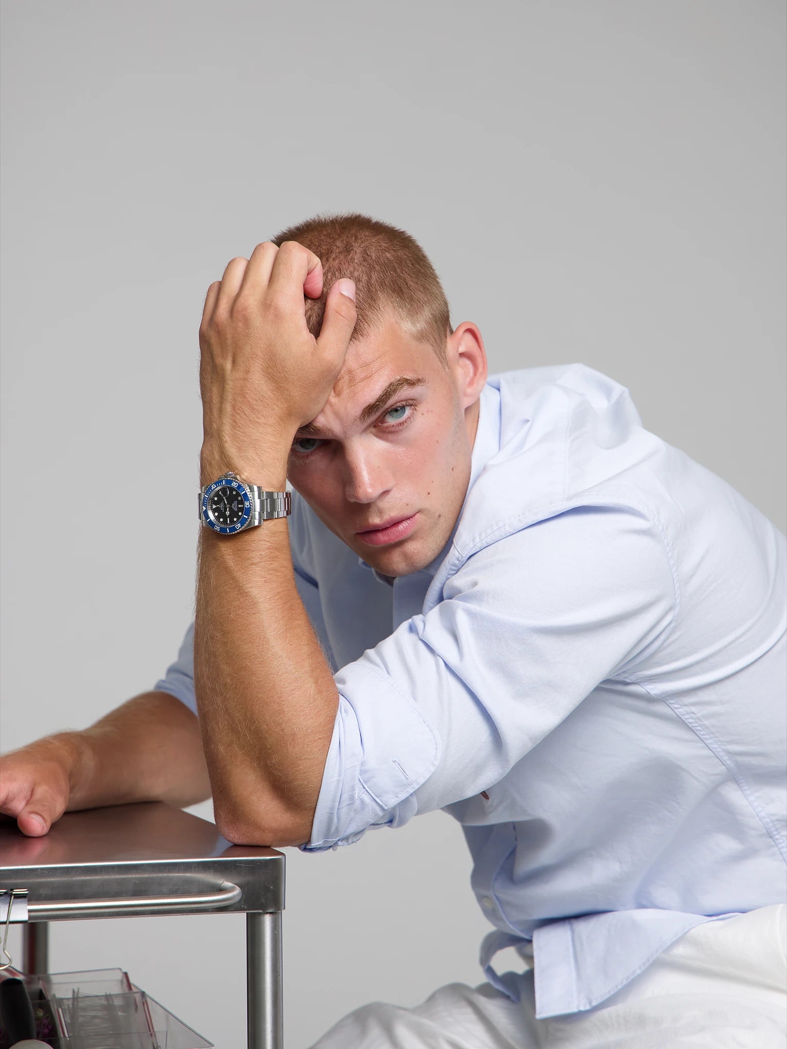 Man wearing a SOREN oceanic blue watch on a oyster bracelet, seated with his arm on a table
