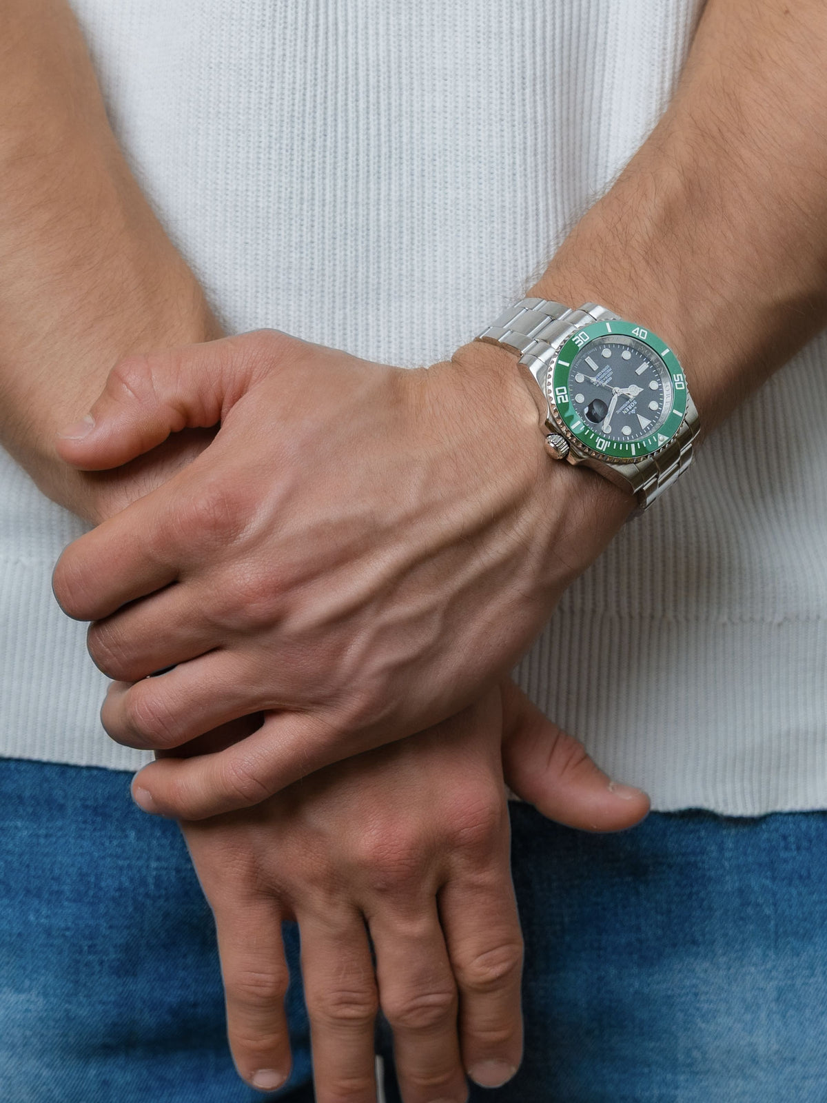 SOREN Oceanic Swiss automatic dive watch with a green bezel on a 3-link steel bracelet, shown with hands clasped together
