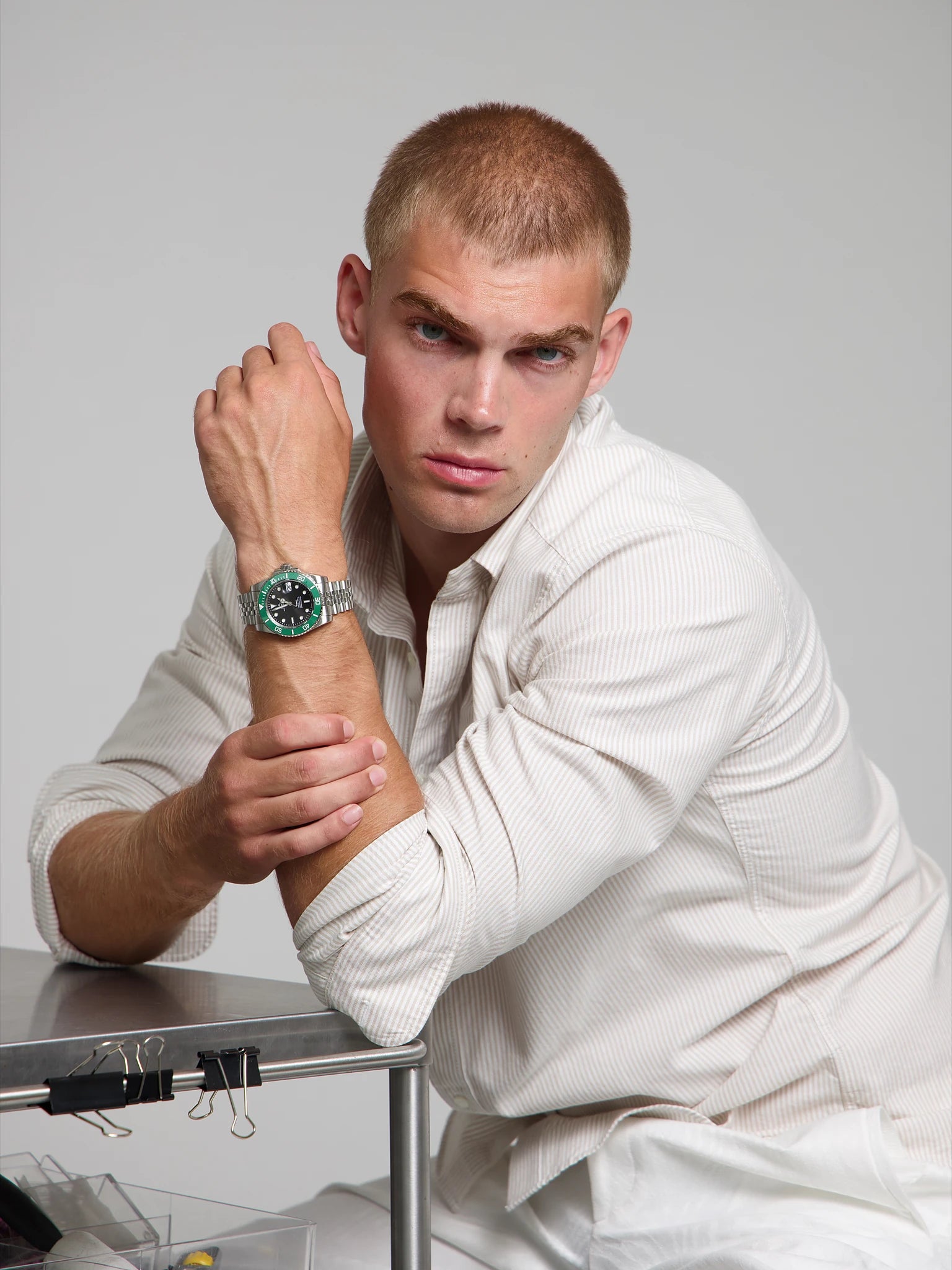 Man wearing a SOREN oceanic green watch on a jubilee bracelet, seated with his arm on a table
