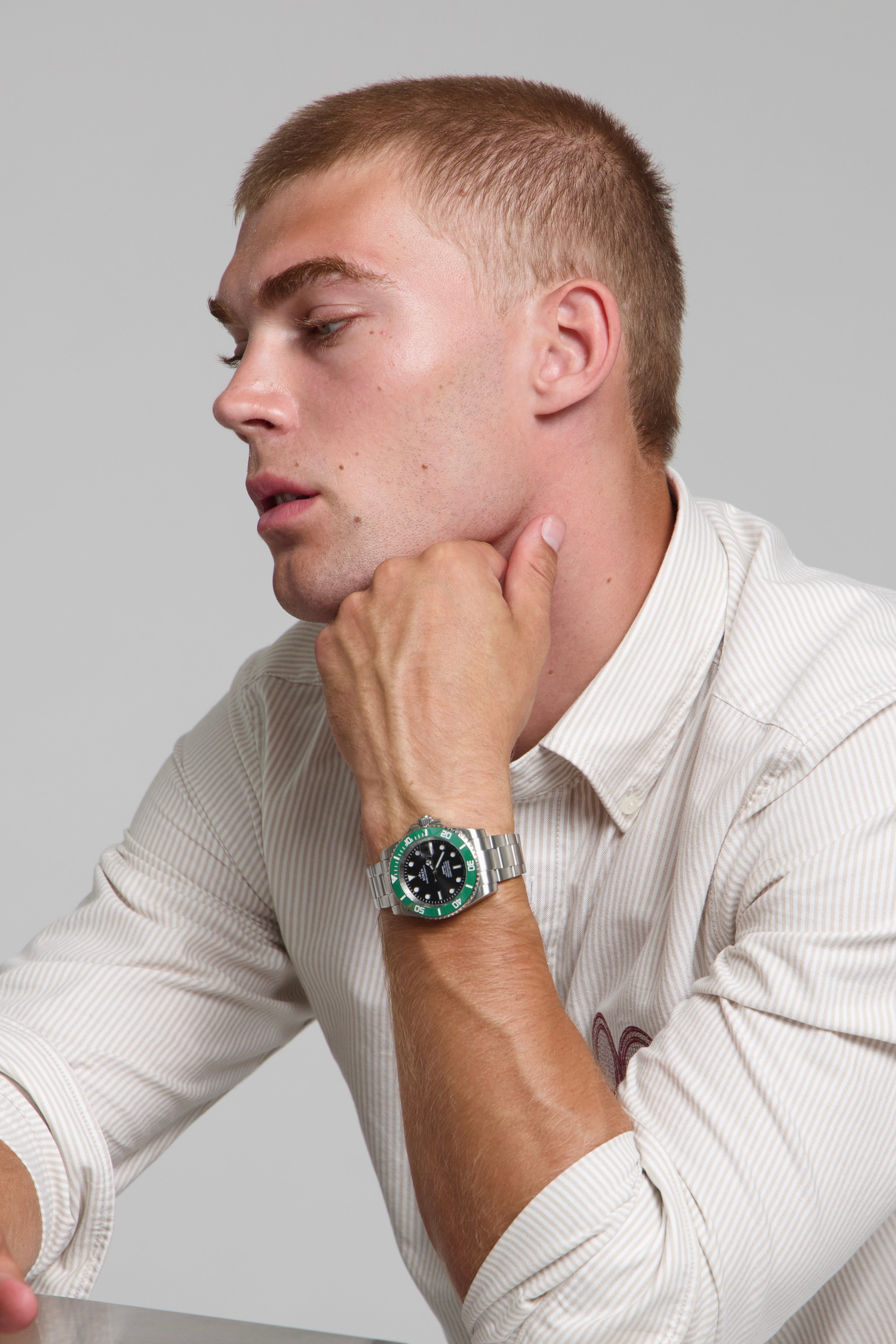 Model wearing a SOREN oceanic green watch on a oyster bracelet, seated
