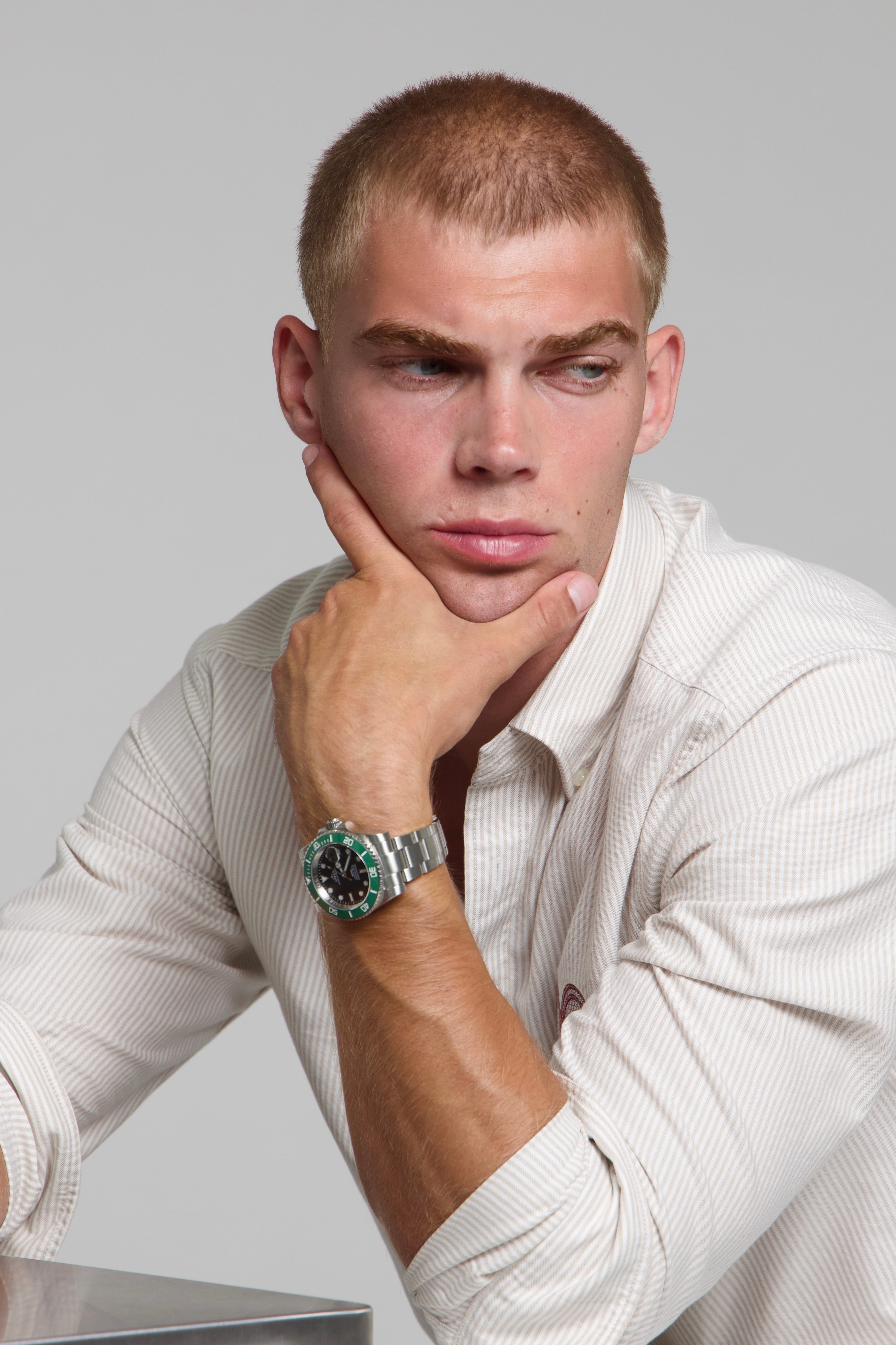 Man wearing a SOREN oceanic green watch on a oyster bracelet, seated with his arm on his leg
